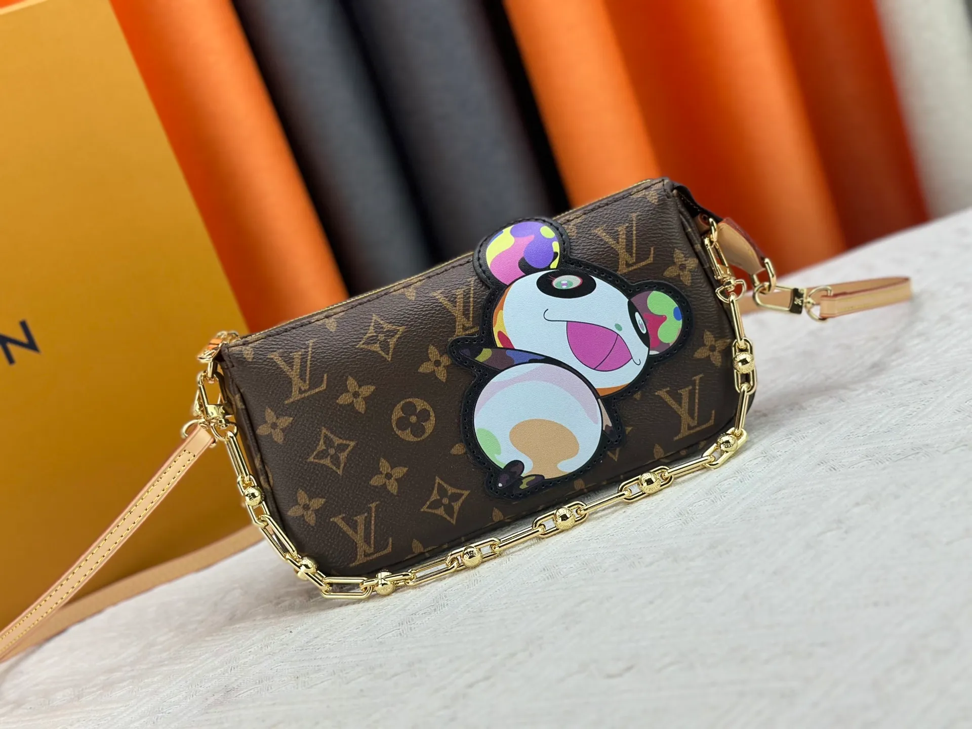 P220 M13440 This Pochette Accessoires handbag is made of Monogram coated canvas, injecting lively personality into the Louis Vuitton x Murakami reissue series. The colorful panda image created by the artist renews the classic silhouette, and the zipper design allows for secure storage of daily items. The cowhide leather shoulder strap and dazzling chain are both detachable, allowing for a variety of carrying options. Size: 22X13X4cm