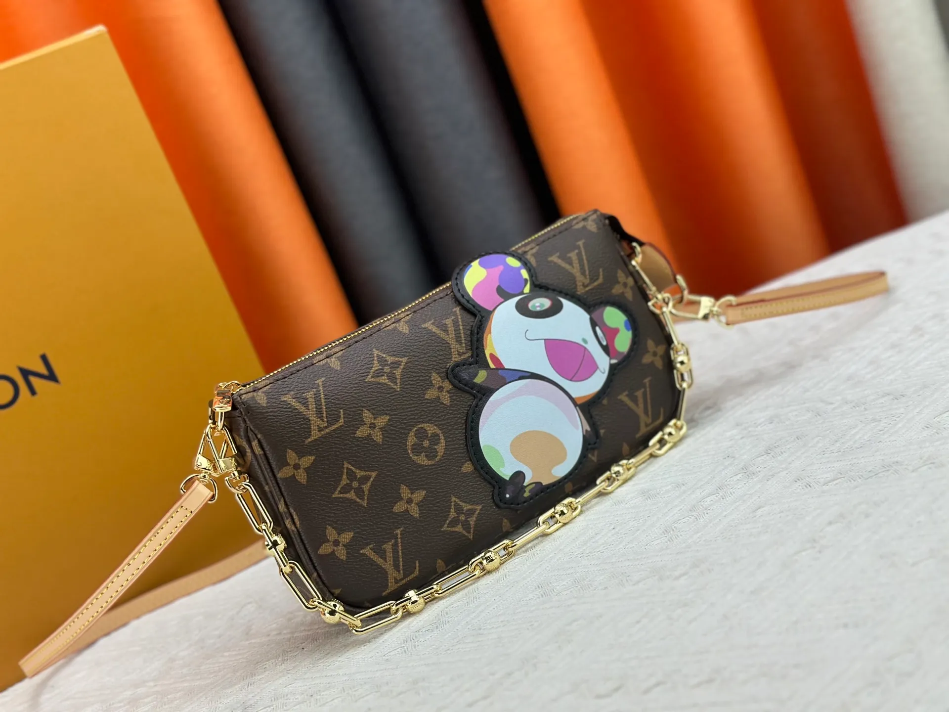 P220 M13440 This Pochette Accessoires handbag is made of Monogram coated canvas, injecting lively personality into the Louis Vuitton x Murakami reissue series. The colorful panda image created by the artist renews the classic silhouette, and the zipper design allows for secure storage of daily items. The cowhide leather shoulder strap and dazzling chain are both detachable, allowing for a variety of carrying options. Size: 22X13X4cm