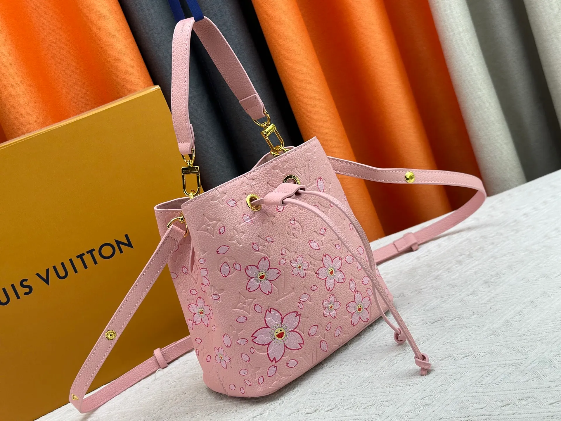 P240 M13676 M44021 This NeoNoe BB bucket bag comes from the Louis Vuitton × Murakami replica series, using Monogram Empreinte leather to convey a fresh breath and smart style. Murakami's signature Cherry Blossom pattern appears on the Monogram embossed surface, and the same floral element is transformed into a slide buckle to tighten the drawstring. Size: 20x20x13cm