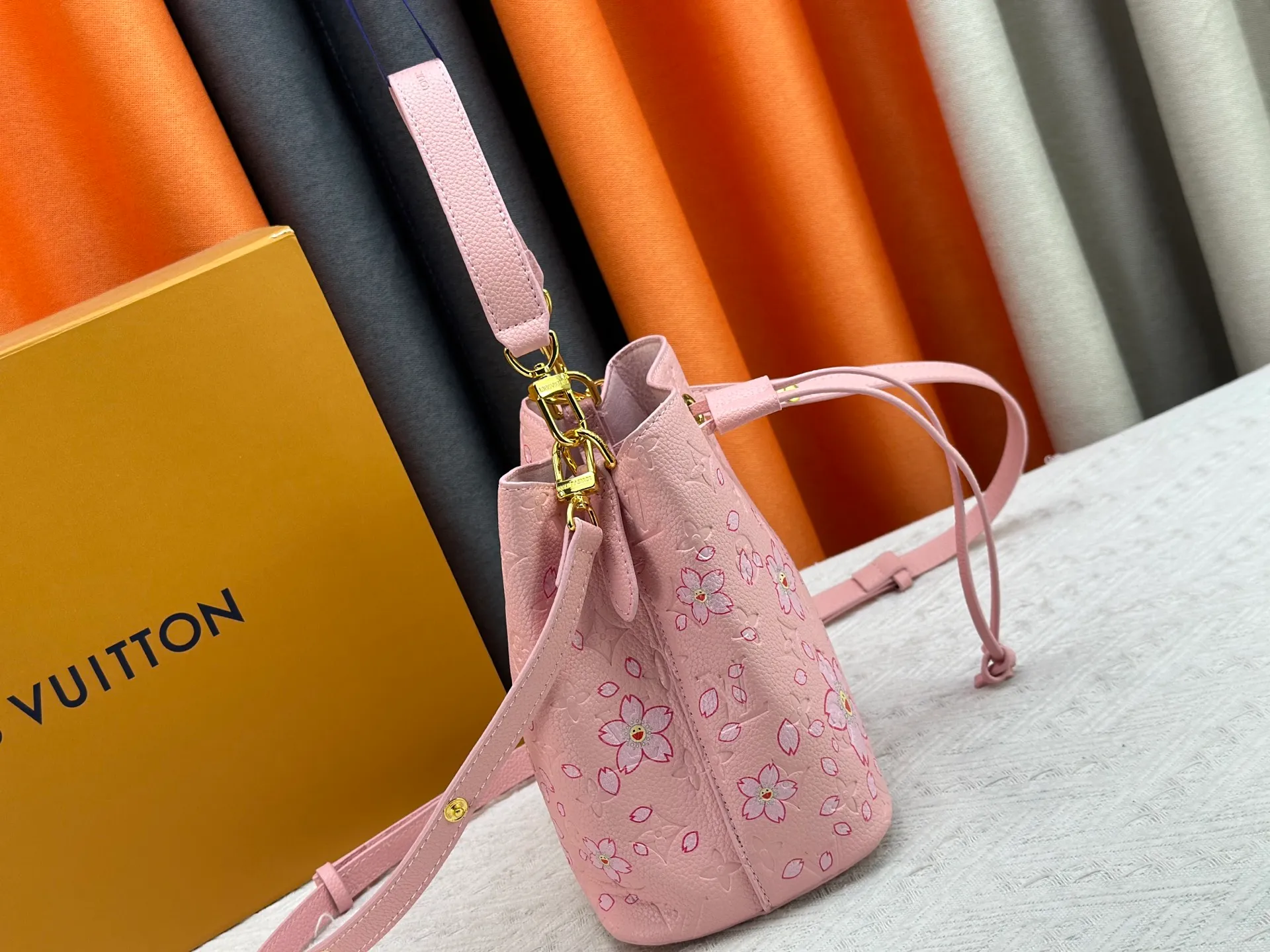 P240 M13676 M44021 This NeoNoe BB bucket bag comes from the Louis Vuitton × Murakami replica series, using Monogram Empreinte leather to convey a fresh breath and smart style. Murakami's signature Cherry Blossom pattern appears on the Monogram embossed surface, and the same floral element is transformed into a slide buckle to tighten the drawstring. Size: 20x20x13cm