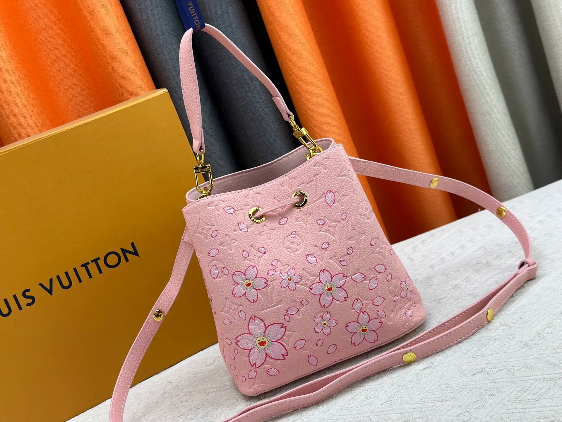 P240 M13676 M44021 This NeoNoe BB bucket bag comes from the Louis Vuitton × Murakami replica series, using Monogram Empreinte leather to convey a fresh breath and smart style. Murakami's signature Cherry Blossom pattern appears on the Monogram embossed surface, and the same floral element is transformed into a slide buckle to tighten the drawstring. Size: 20x20x13cm