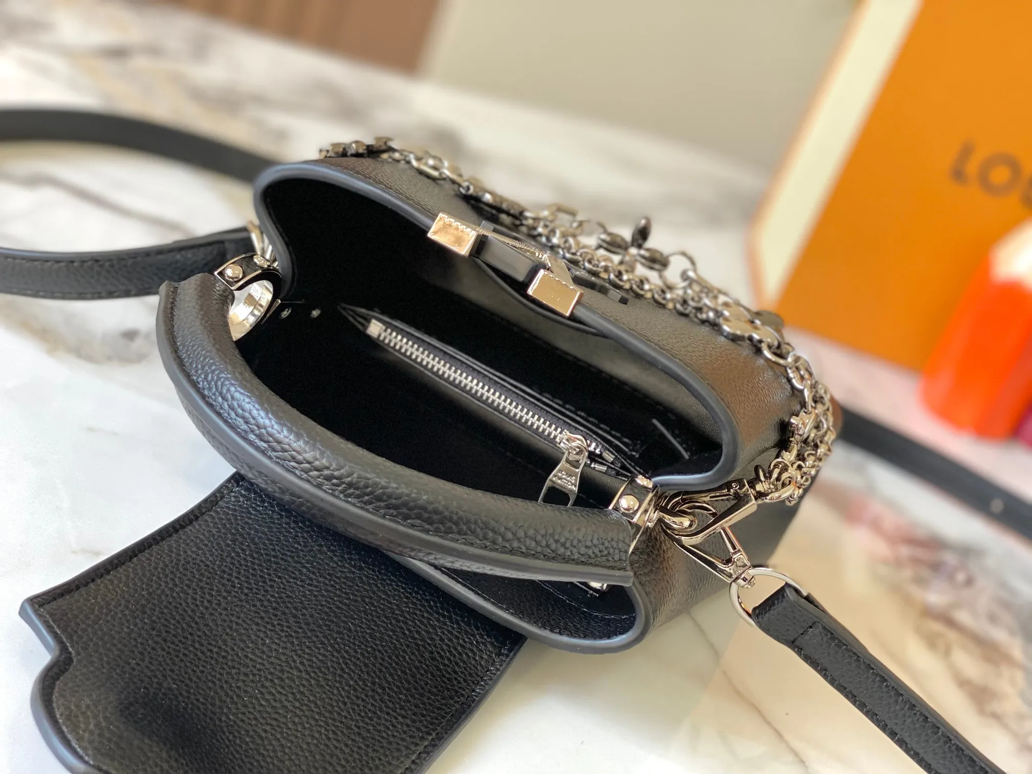 P480 [Guangzhou top quality original version] M26351 Black Silver This modern version of Capucines mini is made of timeless Taurillon leather and equipped with a jewelry-inspired Infinity chain. The bag is decorated with double galvanized metal parts, including the iconic Monogram floral pattern, and the LV Initials logo created with sunburst technology, creating a sundial-like light and shadow effect. The bag has multiple pockets and a detachable shoulder strap, allowing it to be carried on one shoulder or across the body. 14 x 8 x 21 cm (height x width x length)