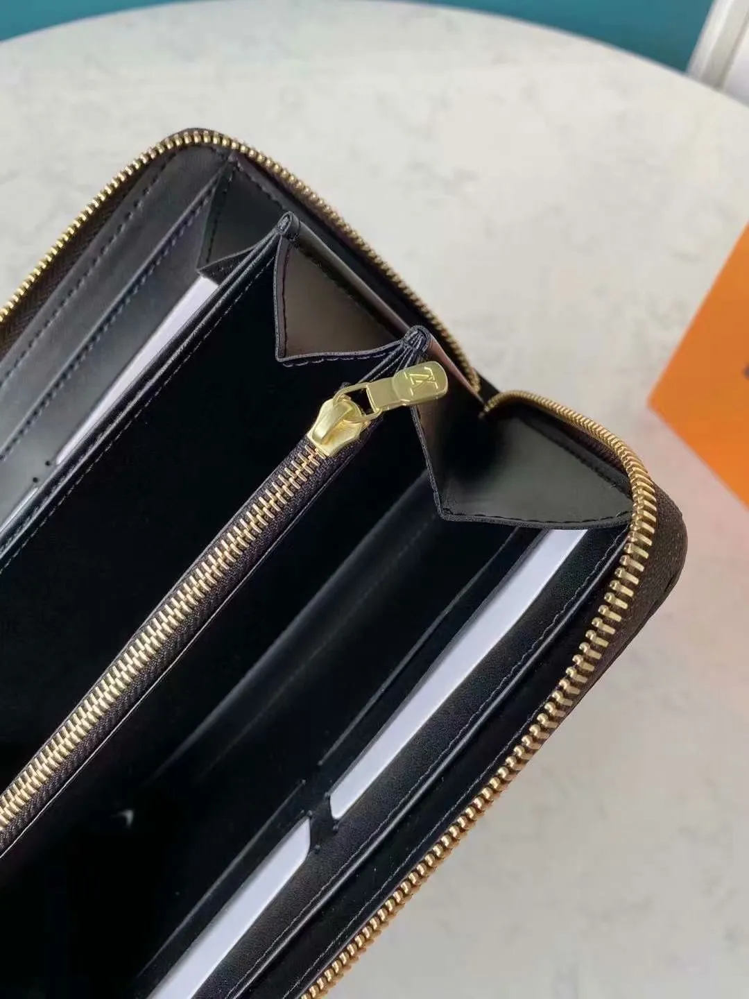 P140M60017 Brown painted small single-pull wallet This Zippy wallet is made of Damier Ebene canvas, with a new lining design and four credit card slots, making it convenient and practical.  Detailed features 19.5x 10.5x 2.5 cm (L x H x W) - Louis Vuitton specially coated canvas - Grained cowhide leather lining - Calfskin trim - Shiny gold-tone hardware - 12 credit card slots - Zippered coin pocket - Open note compartment - 2 internal patch pockets - 3 large paneled compartments - Zip closure