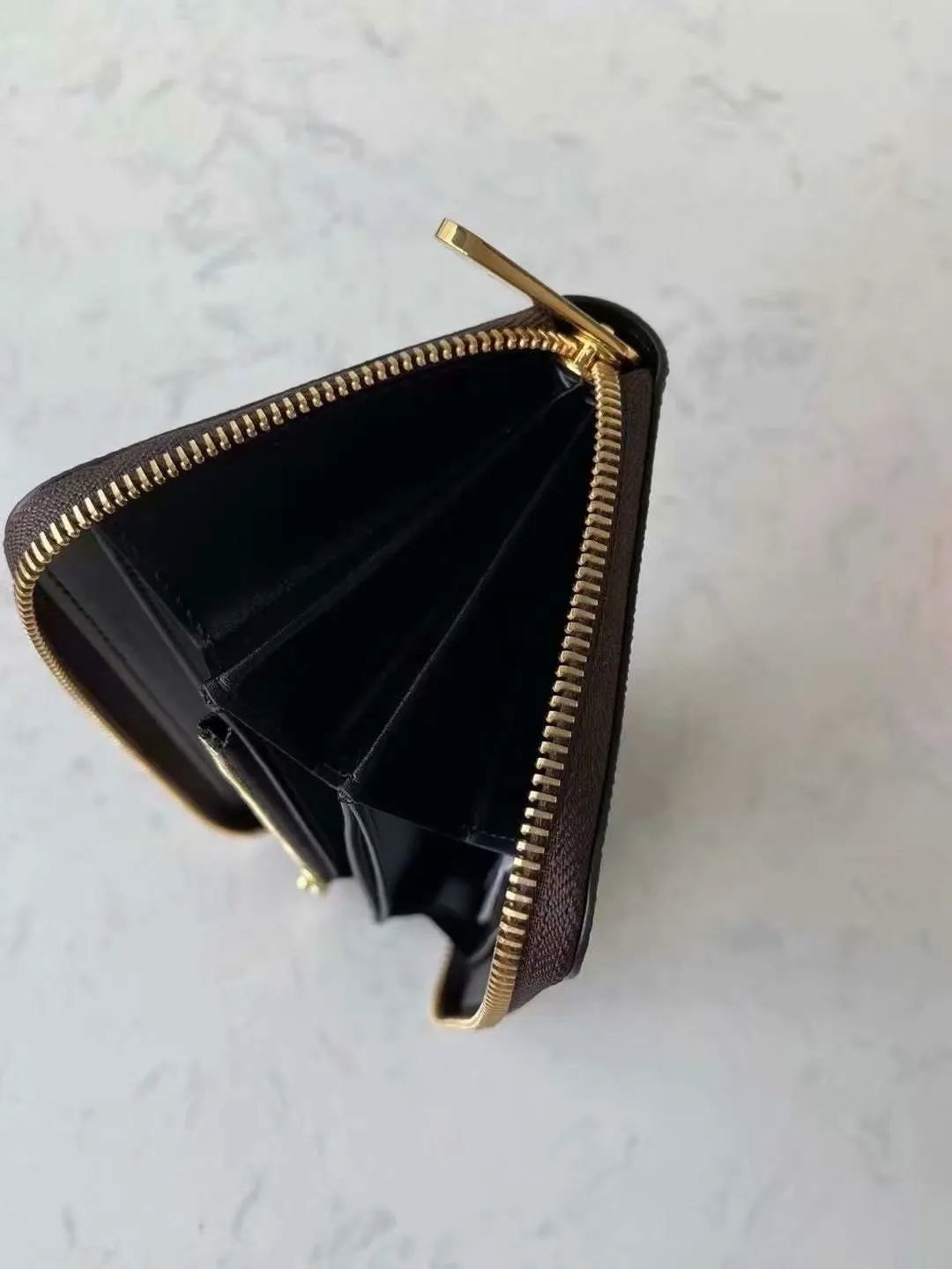 P140M60017 Brown painted small single-pull wallet This Zippy wallet is made of Damier Ebene canvas, with a new lining design and four credit card slots, making it convenient and practical.  Detailed features 19.5x 10.5x 2.5 cm (L x H x W) - Louis Vuitton specially coated canvas - Grained cowhide leather lining - Calfskin trim - Shiny gold-tone hardware - 12 credit card slots - Zippered coin pocket - Open note compartment - 2 internal patch pockets - 3 large paneled compartments - Zip closure