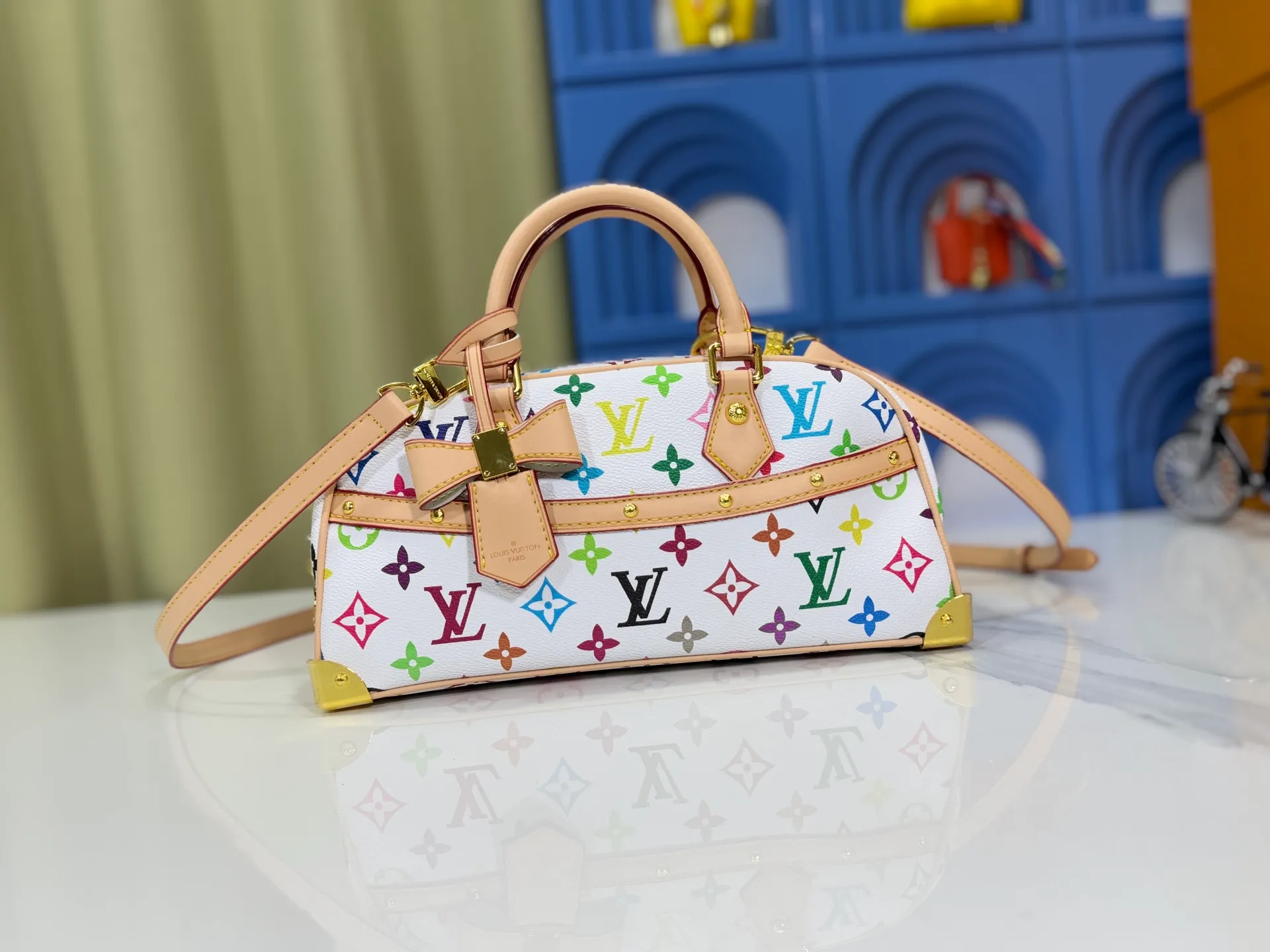 P300 Upgraded Original M13084 This Handbag East West handbag is from the Louis Vuitton x Takashi Murakami reissue series, using the artist's signature rainbow tones to trace the full-length Monogram pattern. Sleek horizontal construction lines the top handle, studded side straps, detachable and adjustable shoulder strap and LV x TM key holder, with cowhide leather details and sophisticated corners that nod to the brand's traditional luggage. Dimensions: 27.0 x 14.0 x 10.0 cm (length x height x width)