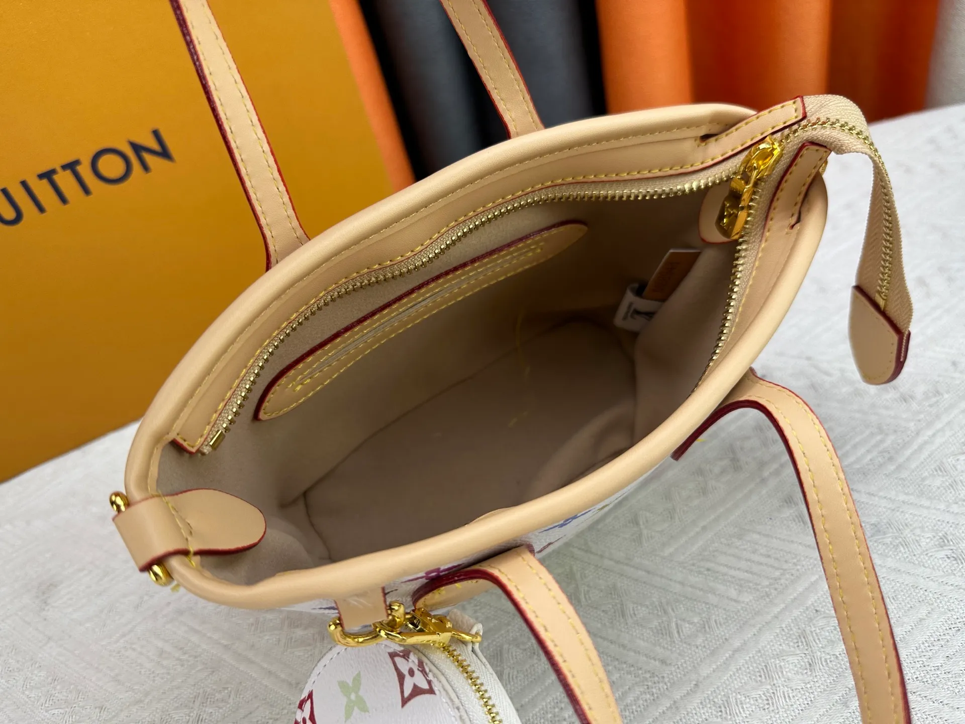 P280 M46705 NEVERFULL BB handbag white tricolor Takashi Murakami co-branded Neverfull classic handbag, explore the exquisite details inside the bag. The redesigned inner bag is equipped with details inspired by the Louis Vuitton archives. The pocket is lined with linen fabric.