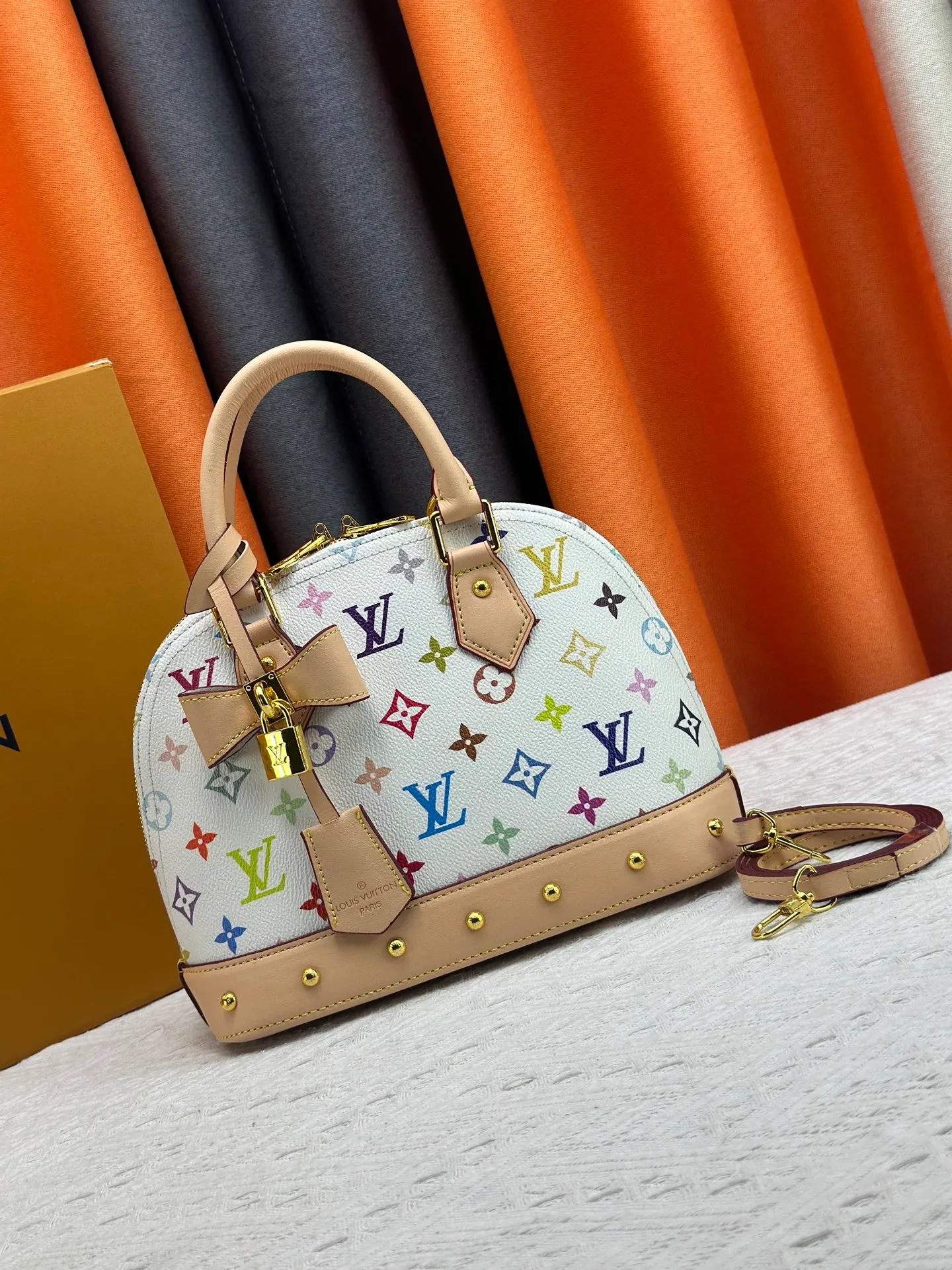 P300 Upgraded original M13078 M53152 This Alma BB handbag exudes the cheerful style of the Louis Vuitton x Murakami collaboration series, cleverly recalling the Art Deco design of the 1930s. Monogram coated canvas renders Murakami's playful tones, while classic calfskin touches the Toron handle, base, detachable shoulder strap and LV x TM key holder. 17.5 x 11.5 x 23.5 cm (height x width x length)