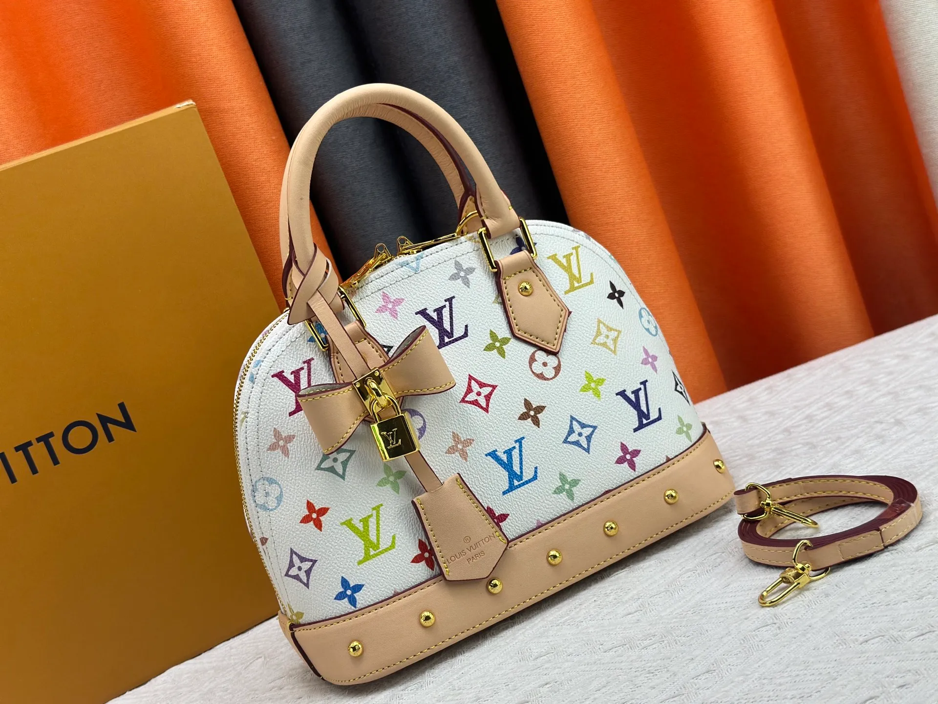 P300 Upgraded original M13078 M53152 This Alma BB handbag exudes the cheerful style of the Louis Vuitton x Murakami collaboration series, cleverly recalling the Art Deco design of the 1930s. Monogram coated canvas renders Murakami's playful tones, while classic calfskin touches the Toron handle, base, detachable shoulder strap and LV x TM key holder. 17.5 x 11.5 x 23.5 cm (height x width x length)