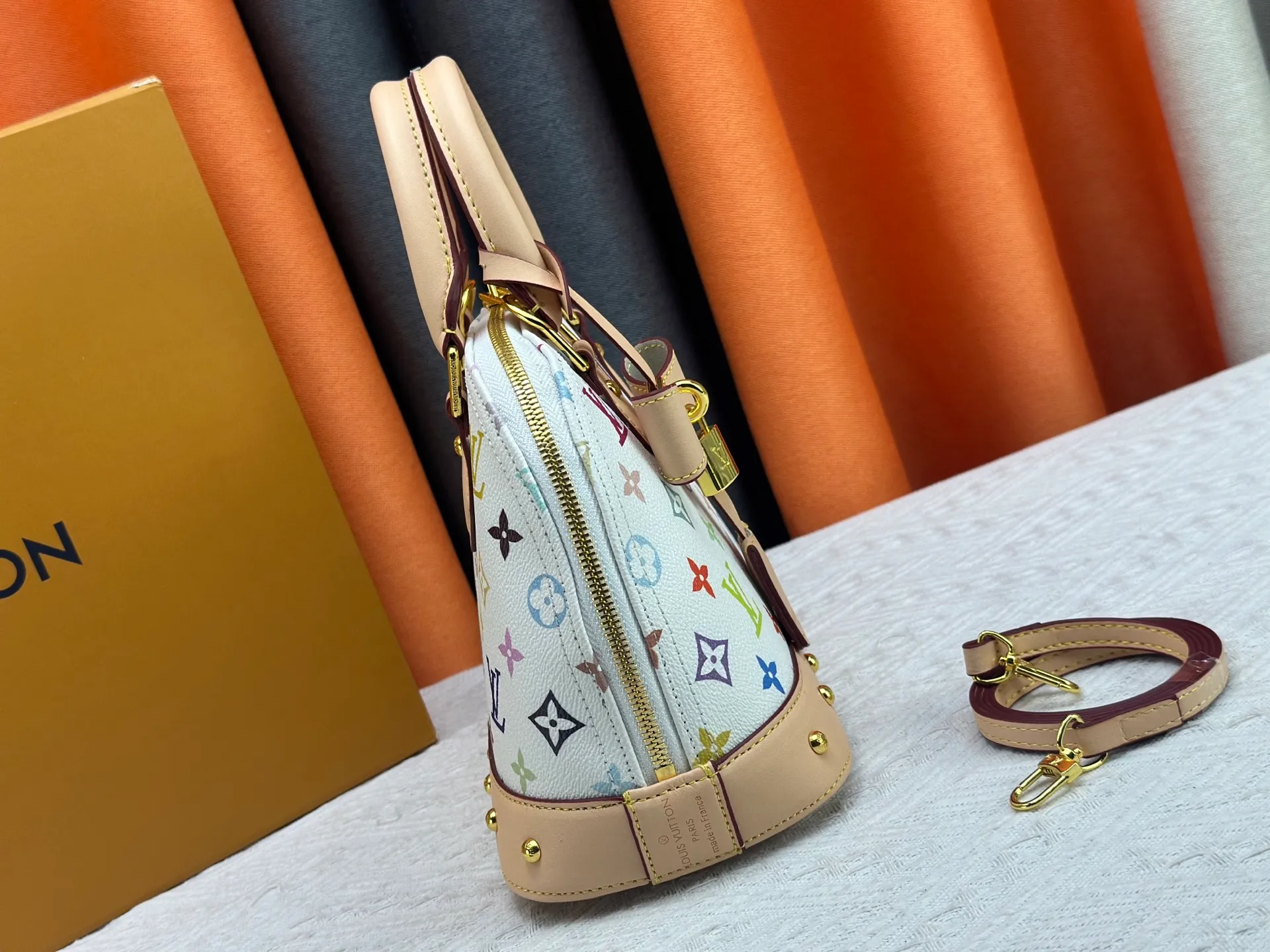 P300 Upgraded original M13078 M53152 This Alma BB handbag exudes the cheerful style of the Louis Vuitton x Murakami collaboration series, cleverly recalling the Art Deco design of the 1930s. Monogram coated canvas renders Murakami's playful tones, while classic calfskin touches the Toron handle, base, detachable shoulder strap and LV x TM key holder. 17.5 x 11.5 x 23.5 cm (height x width x length)