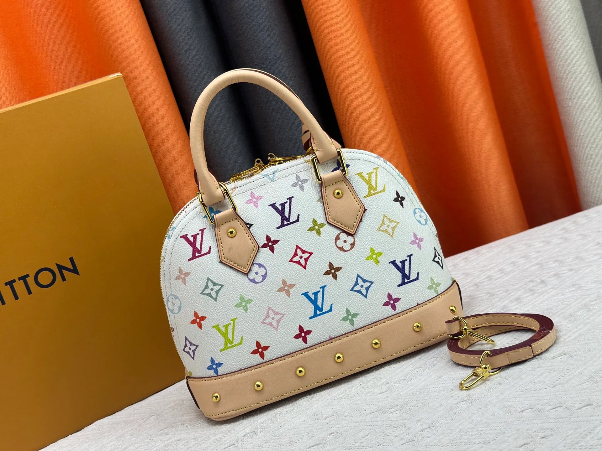 P300 Upgraded original M13078 M53152 This Alma BB handbag exudes the cheerful style of the Louis Vuitton x Murakami collaboration series, cleverly recalling the Art Deco design of the 1930s. Monogram coated canvas renders Murakami's playful tones, while classic calfskin touches the Toron handle, base, detachable shoulder strap and LV x TM key holder. 17.5 x 11.5 x 23.5 cm (height x width x length)