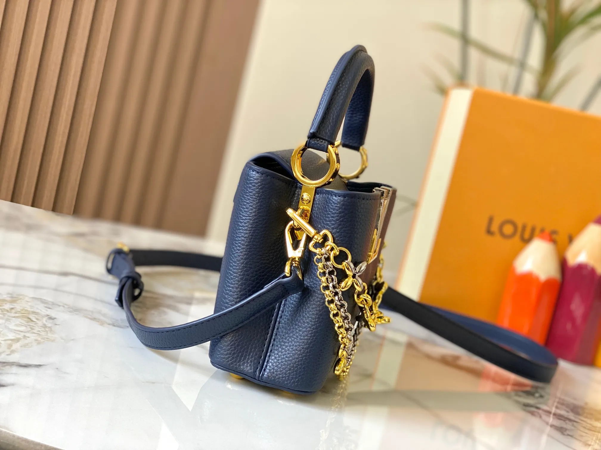 P480 [Guangzhou top quality original version] M26351 Blue This modern version of the Capucines mini is made of timeless Taurillon leather and equipped with a jewelry-inspired Infinity chain. The bag is decorated with double galvanized metal parts, including the iconic Monogram floral pattern, and the LV Initials logo created with sunburst technology, creating a sundial-like light and shadow effect. The bag has multiple pockets and a detachable shoulder strap, allowing it to be carried on one shoulder or across the body. 14 x 8 x 21 cm (height x width x length)