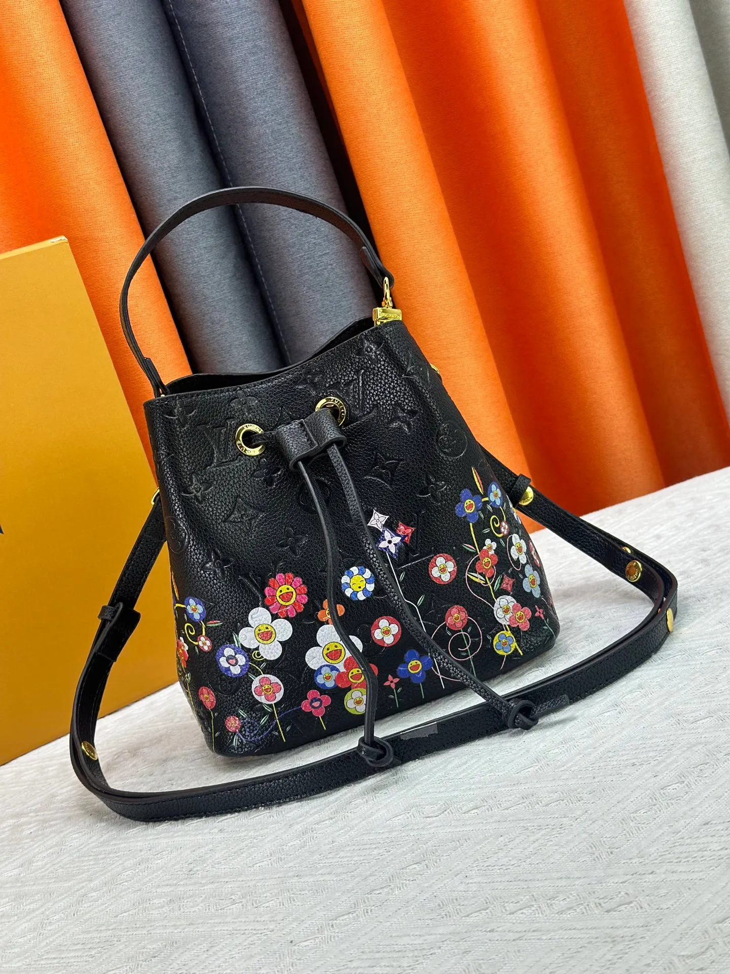 P240 M13676 M44021 This NeoNoe BB bucket bag comes from the Louis Vuitton × Murakami replica series, using Monogram Empreinte leather to convey a fresh breath and smart style. Murakami's signature Cherry Blossom pattern appears on the Monogram embossed surface, and the same floral element is transformed into a slide buckle to tighten the drawstring. Size: 20x20x13cm