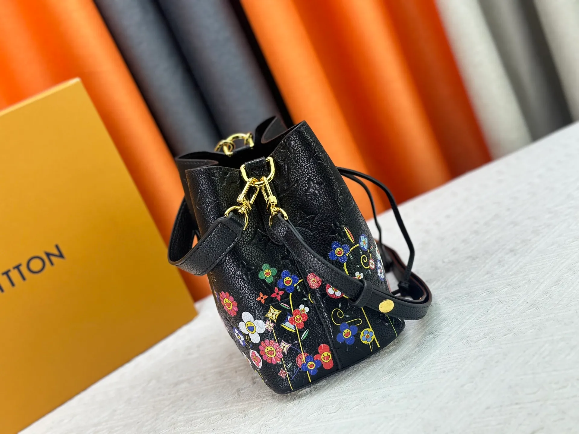 P240 M13676 M44021 This NeoNoe BB bucket bag comes from the Louis Vuitton × Murakami replica series, using Monogram Empreinte leather to convey a fresh breath and smart style. Murakami's signature Cherry Blossom pattern appears on the Monogram embossed surface, and the same floral element is transformed into a slide buckle to tighten the drawstring. Size: 20x20x13cm