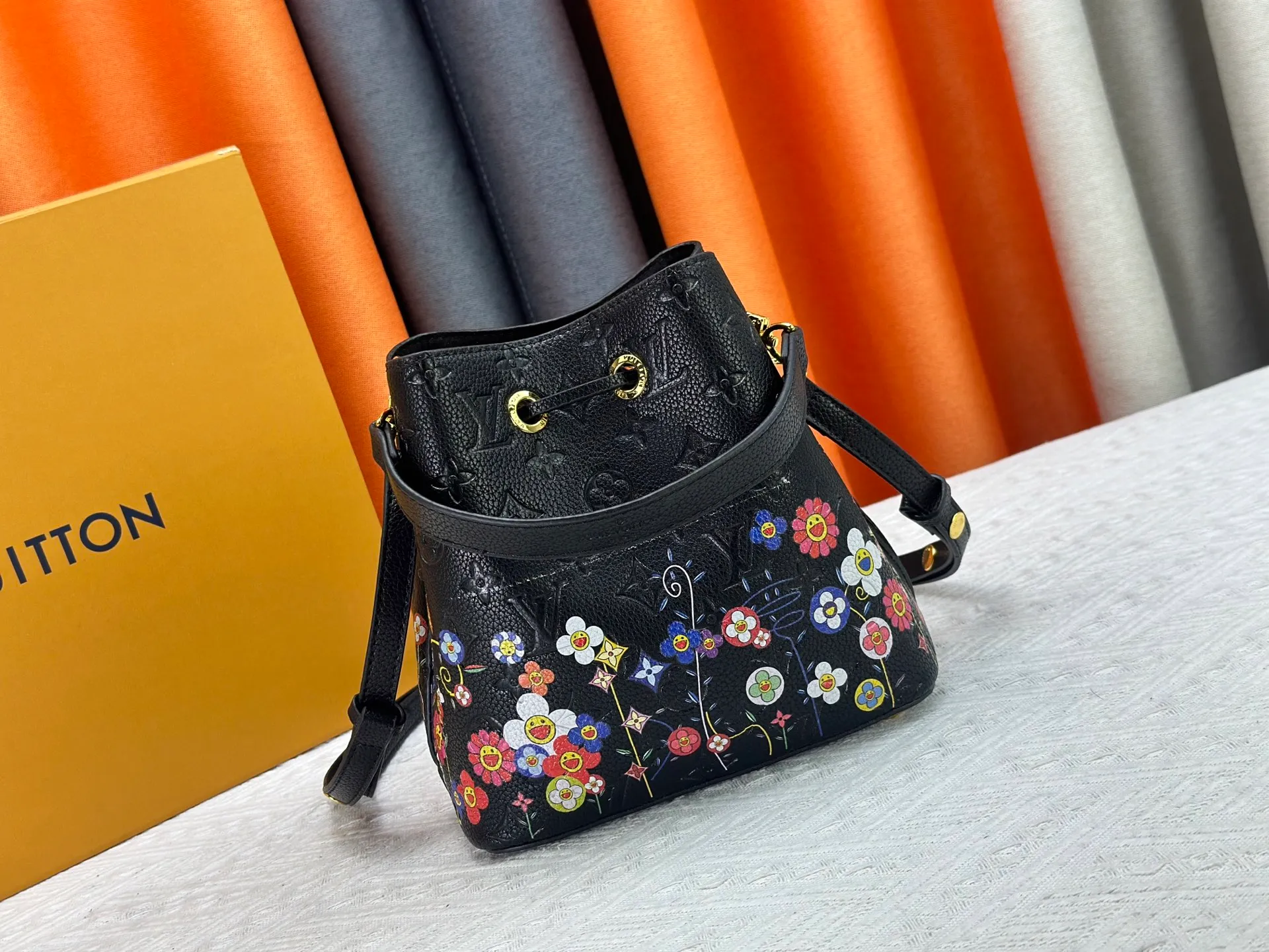P240 M13676 M44021 This NeoNoe BB bucket bag comes from the Louis Vuitton × Murakami replica series, using Monogram Empreinte leather to convey a fresh breath and smart style. Murakami's signature Cherry Blossom pattern appears on the Monogram embossed surface, and the same floral element is transformed into a slide buckle to tighten the drawstring. Size: 20x20x13cm