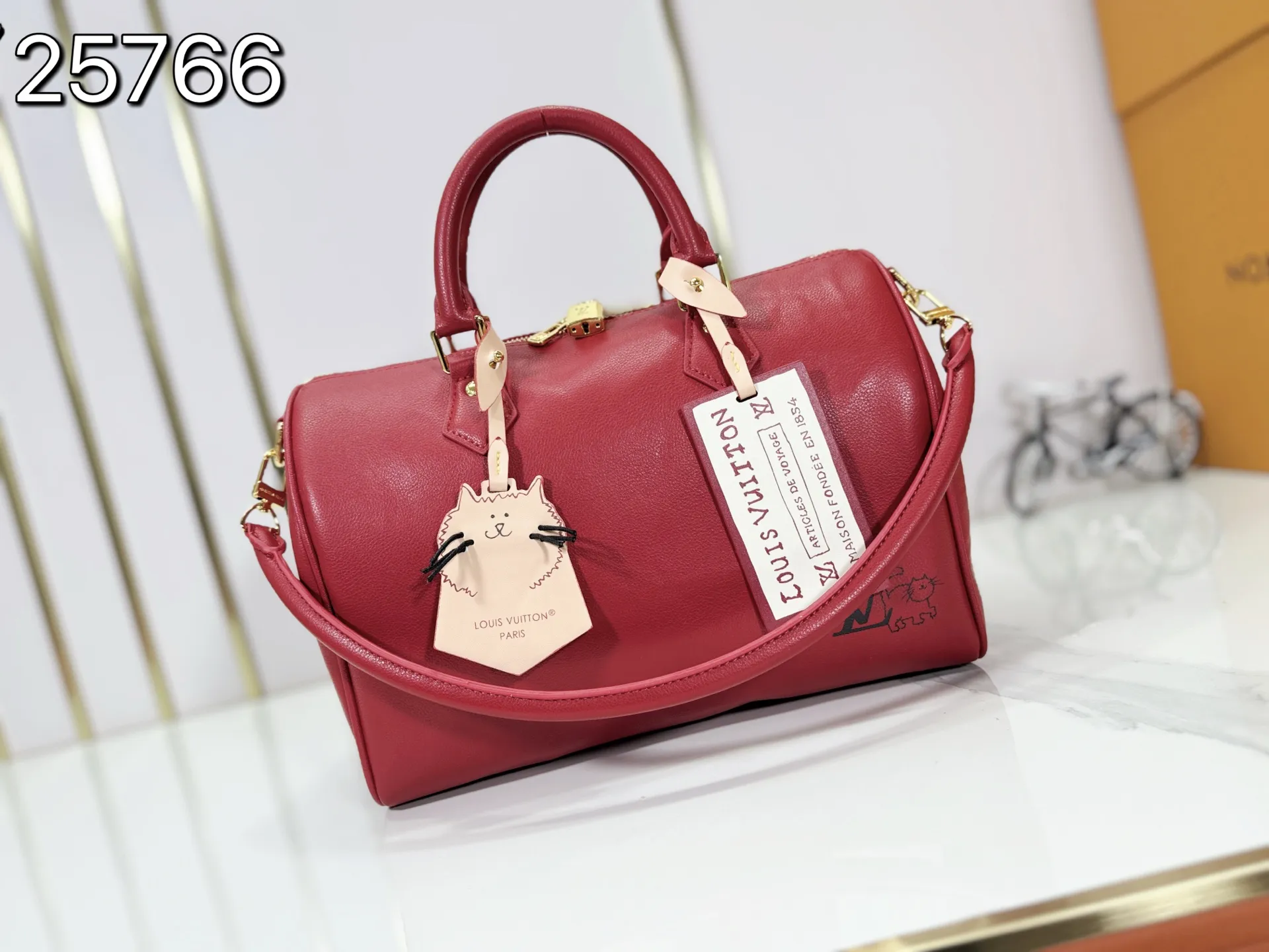 P260 M25766 M24424 M24425 Size: 30×21×17CM [SPEEDY SOFT 30 handbag] This Speedy Soft 30 is from the LV Travels With Grace Coddington series. It is made of rich-toned cow leather with metal parts and a fun cat-shaped key bag. Removable name tag features Grace Coddington's handwriting.