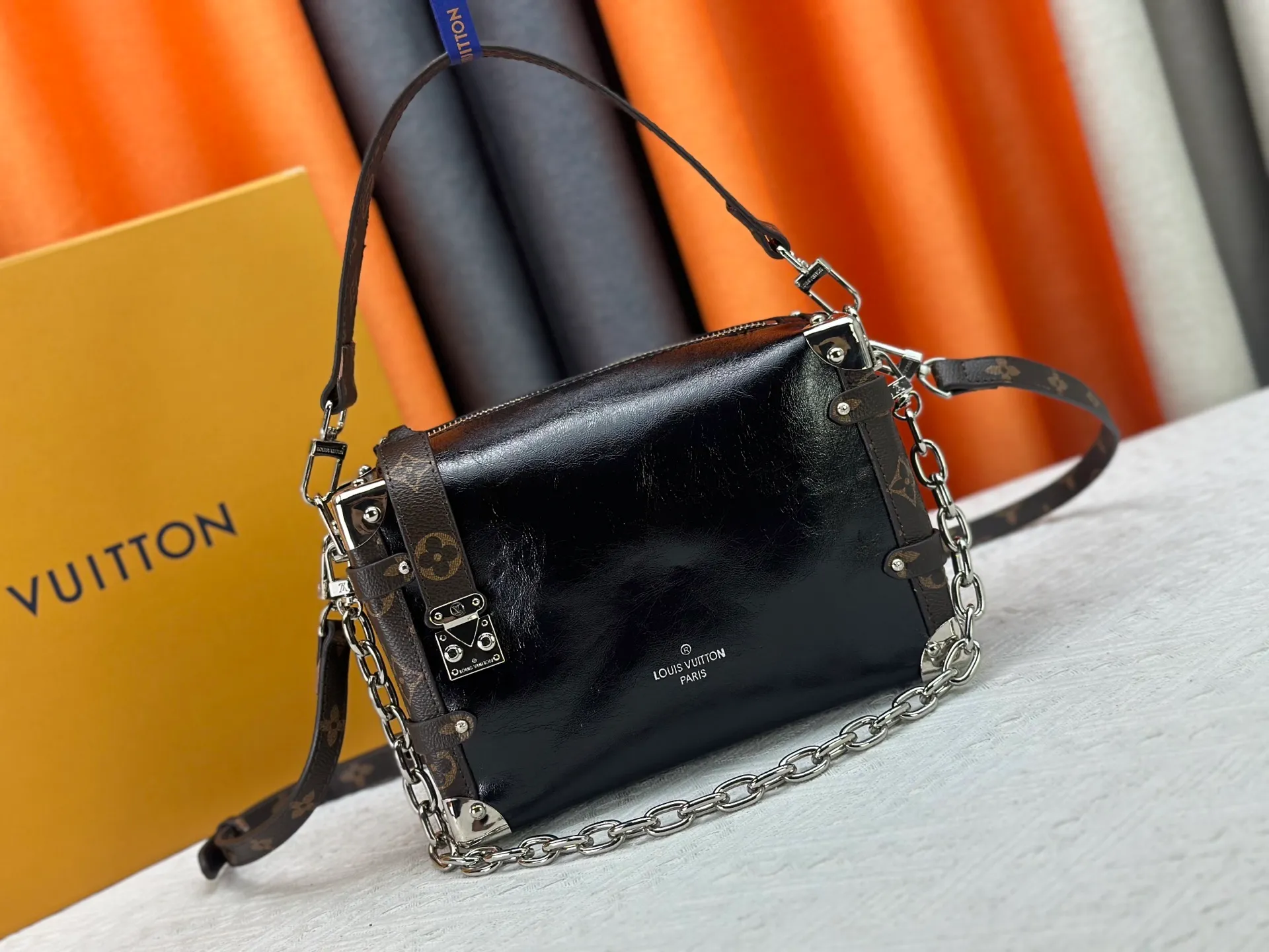 P300 M15195 M46358 This Side Trunk Vibe handbag reimagines the brand's classic Side Trunk silhouette with an avant-garde design, inspired by Louis Vuitton's traditional travel trunks. Crafted from smooth glossy Vibe textured cow leather, it features a leather-covered rivet frame and metal S-lock closure for a rock-and-roll style. Thanks to the multiple designs of the detachable chain, detachable leather handle and adjustable leather shoulder strap, it provides a variety of carrying options. Dimensions: 23.5x16x8.5cm
