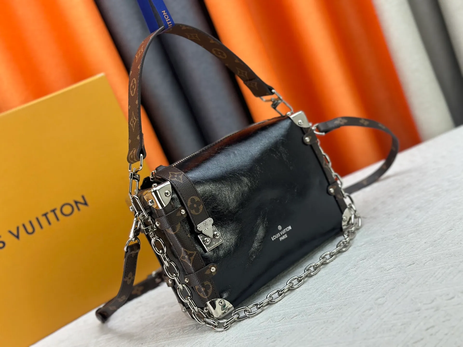 P300 M15195 M46358 This Side Trunk Vibe handbag reimagines the brand's classic Side Trunk silhouette with an avant-garde design, inspired by Louis Vuitton's traditional travel trunks. Crafted from smooth glossy Vibe textured cow leather, it features a leather-covered rivet frame and metal S-lock closure for a rock-and-roll style. Thanks to the multiple designs of the detachable chain, detachable leather handle and adjustable leather shoulder strap, it provides a variety of carrying options. Dimensions: 23.5x16x8.5cm