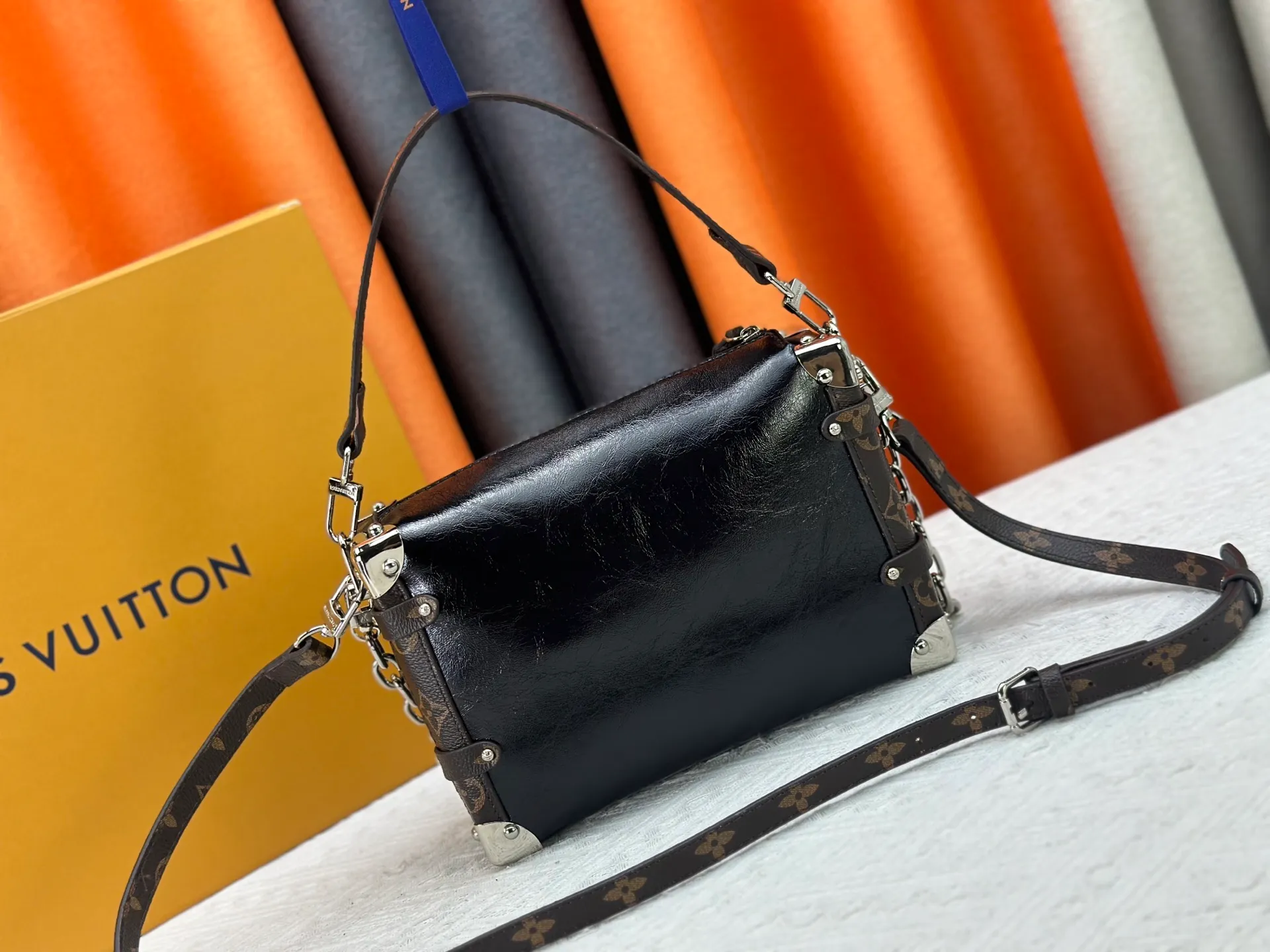 P300 M15195 M46358 This Side Trunk Vibe handbag reimagines the brand's classic Side Trunk silhouette with an avant-garde design, inspired by Louis Vuitton's traditional travel trunks. Crafted from smooth glossy Vibe textured cow leather, it features a leather-covered rivet frame and metal S-lock closure for a rock-and-roll style. Thanks to the multiple designs of the detachable chain, detachable leather handle and adjustable leather shoulder strap, it provides a variety of carrying options. Dimensions: 23.5x16x8.5cm