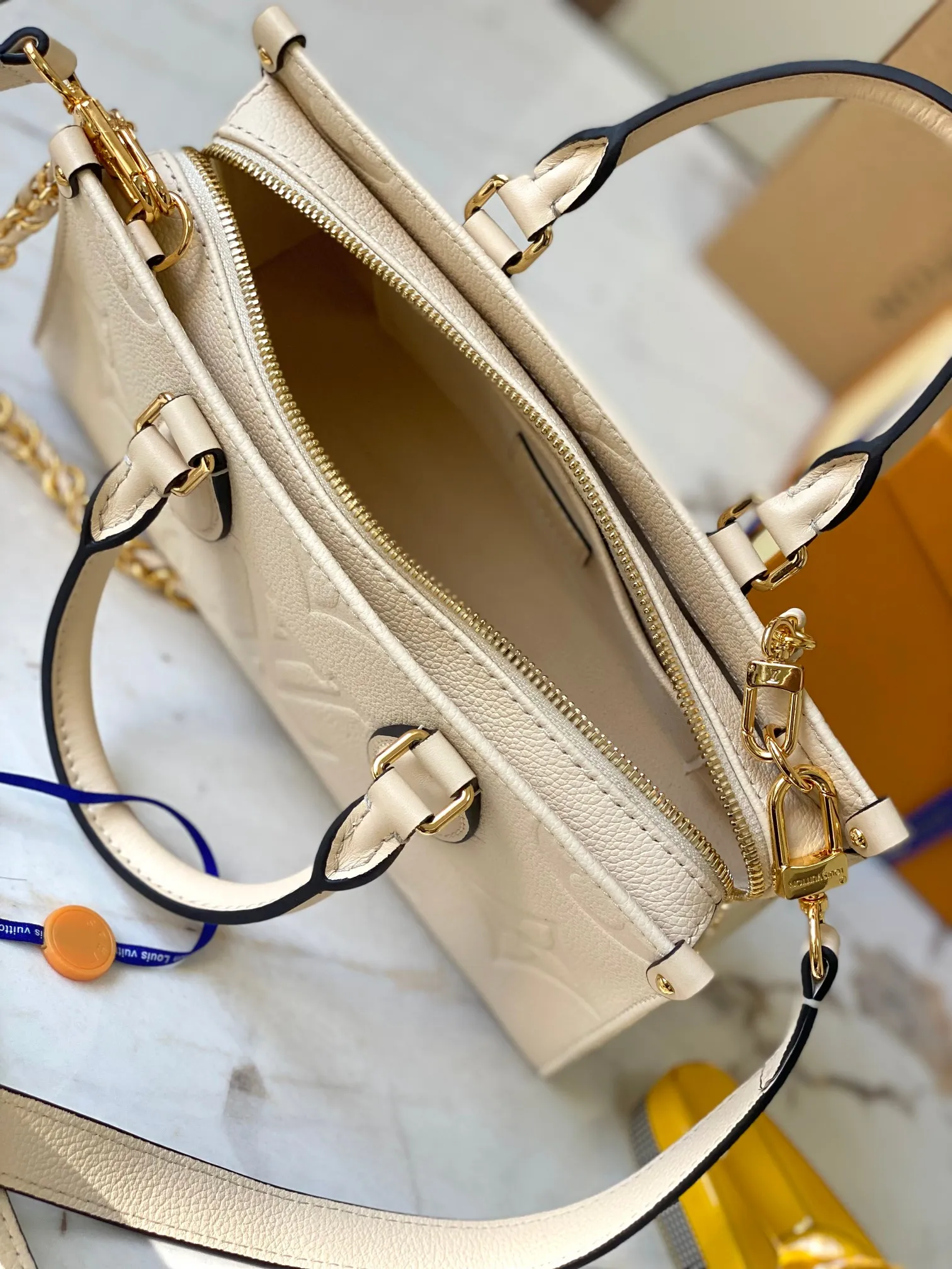 P1440 [Original leather 💋 M23698 milk white] [OnTheGo East West handbag] Introducing the design of Ays OnTheGo small tote bag, using Monogram Empreinte leather to reinterpret the ample configuration of East West. The Giant Monogram is embossed on the leather body, and the neat interior can store daily necessities. The top handle and removable leather chain strap allow for multiple carry options.  Dimensions: 25.0 x 13.0 x 10.0 cmP