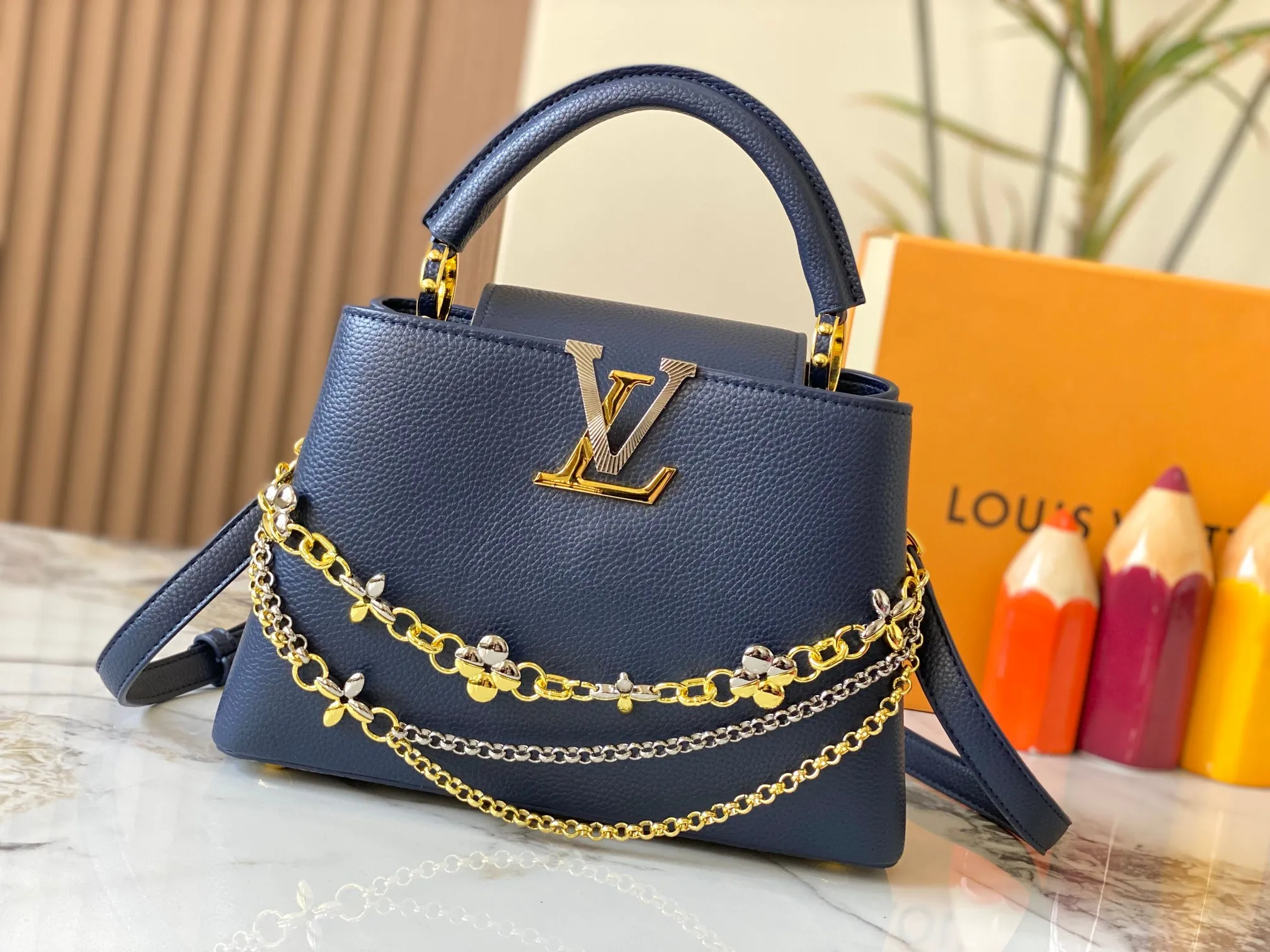 P500 [Guangzhou top quality original version] M26532 Blue This modern version of Capucines BB is made of timeless Taurillon leather and equipped with a jewelry-inspired Infinity chain. The bag is decorated with double galvanized metal parts, including the iconic Monogram floral pattern, and the LV Initials logo created with sunburst technology, creating a sundial-like light and shadow effect. The bag has multiple pockets and a detachable shoulder strap, allowing it to be carried on one shoulder or across the body. 27 x 17.3 x 9 (cm) (length x height x width)