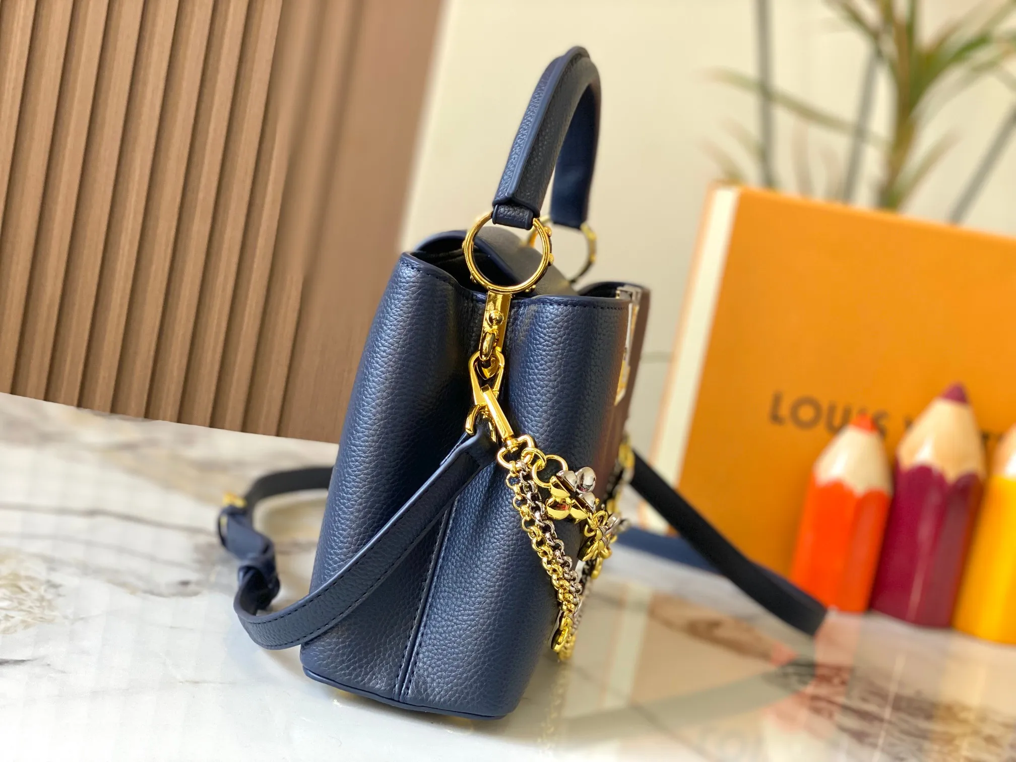 P500 [Guangzhou top quality original version] M26532 Blue This modern version of Capucines BB is made of timeless Taurillon leather and equipped with a jewelry-inspired Infinity chain. The bag is decorated with double galvanized metal parts, including the iconic Monogram floral pattern, and the LV Initials logo created with sunburst technology, creating a sundial-like light and shadow effect. The bag has multiple pockets and a detachable shoulder strap, allowing it to be carried on one shoulder or across the body. 27 x 17.3 x 9 (cm) (length x height x width)