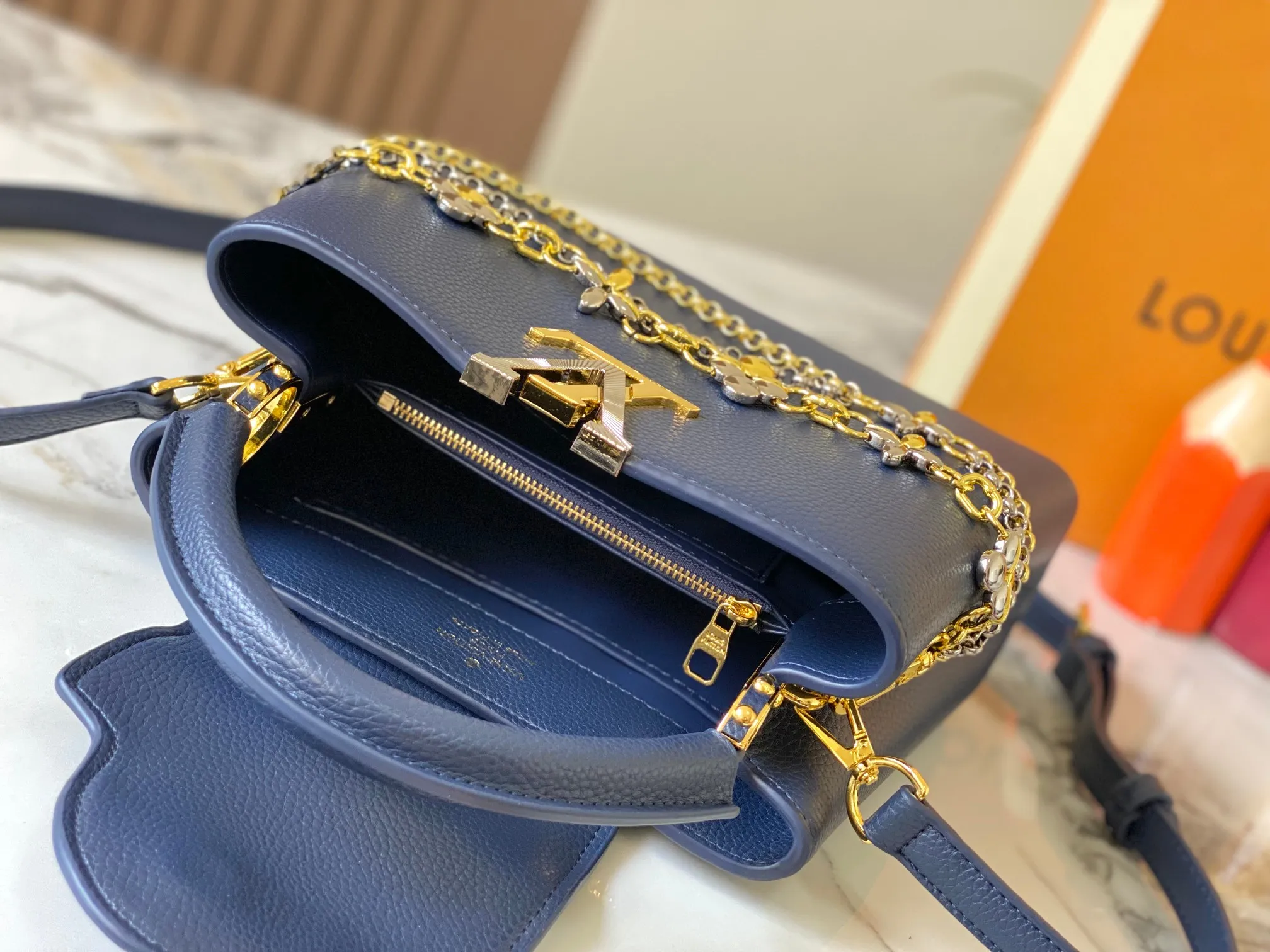 P500 [Guangzhou top quality original version] M26532 Blue This modern version of Capucines BB is made of timeless Taurillon leather and equipped with a jewelry-inspired Infinity chain. The bag is decorated with double galvanized metal parts, including the iconic Monogram floral pattern, and the LV Initials logo created with sunburst technology, creating a sundial-like light and shadow effect. The bag has multiple pockets and a detachable shoulder strap, allowing it to be carried on one shoulder or across the body. 27 x 17.3 x 9 (cm) (length x height x width)