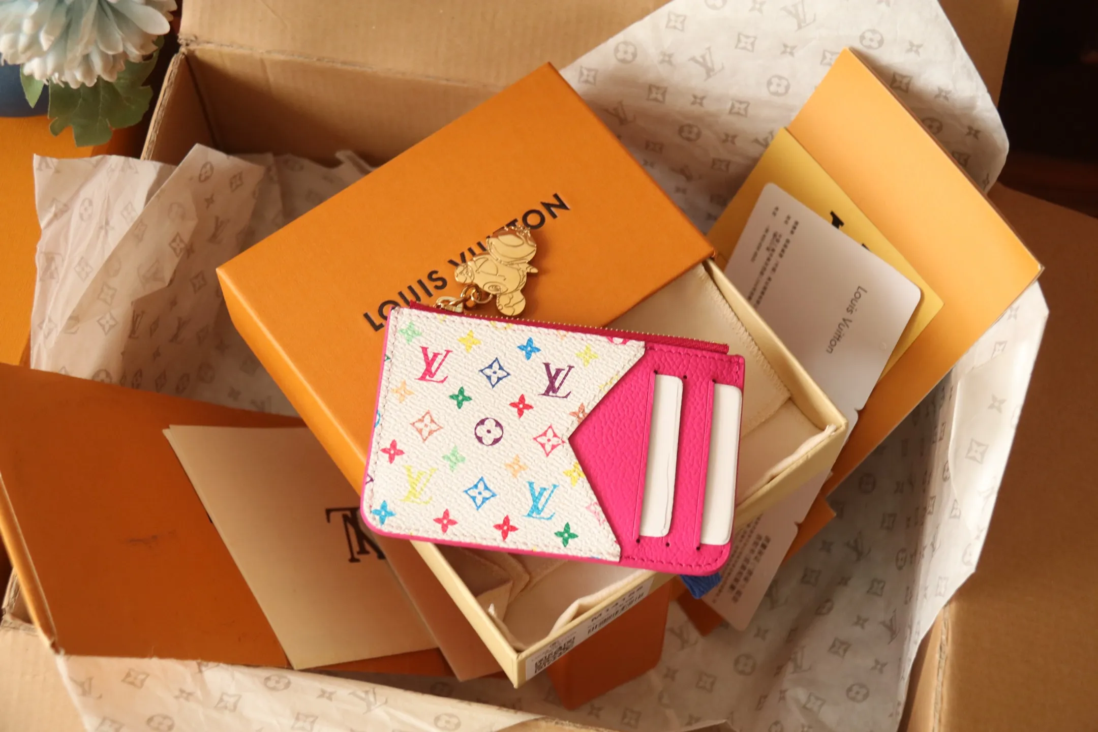 【LV x TM Romy Card Holder】 💎P400 m14155 Rose m14171 Blue m13800 Green "LV × TM Porto Kurt Romy" appears in the "Louis Vuitton × Takashi Murakami" series that unfolds in a variety of categories. It features functional and playful expressions with fresh tones inspired by the rainbow colors unique to Japanese artists. The whole piece is finished with Monogram Amplant leather that adds a casual personality, and the bright Monogram multi-color canvas in the flat pocket stands out. The coin pocket opens and closes with a gold zipper and features a panda pull to symbolize the season.  Dimensions: 12 x 8 x 0.8 cm