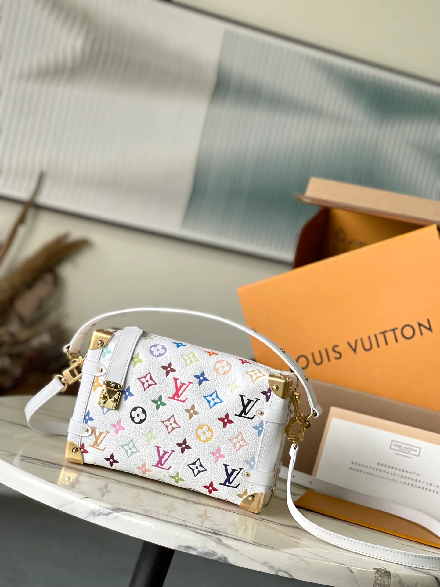 💰1220 (first-grain leather) Top-quality original item M14046 This medium-sized Side Trunk handbag uses a humorous Monogram pattern to express the smart style of the x Murakami Takashi reissue series. It is made of soft cow leather with reinforced metal corners and the iconic S-lock lock, which can easily accommodate daily needs. The square shape is a nod to the brand's classic luggage, and the removable studded handle and shoulder strap allow for flexible carrying. Dimensions: 23.5 × 16 × 8.5 cm