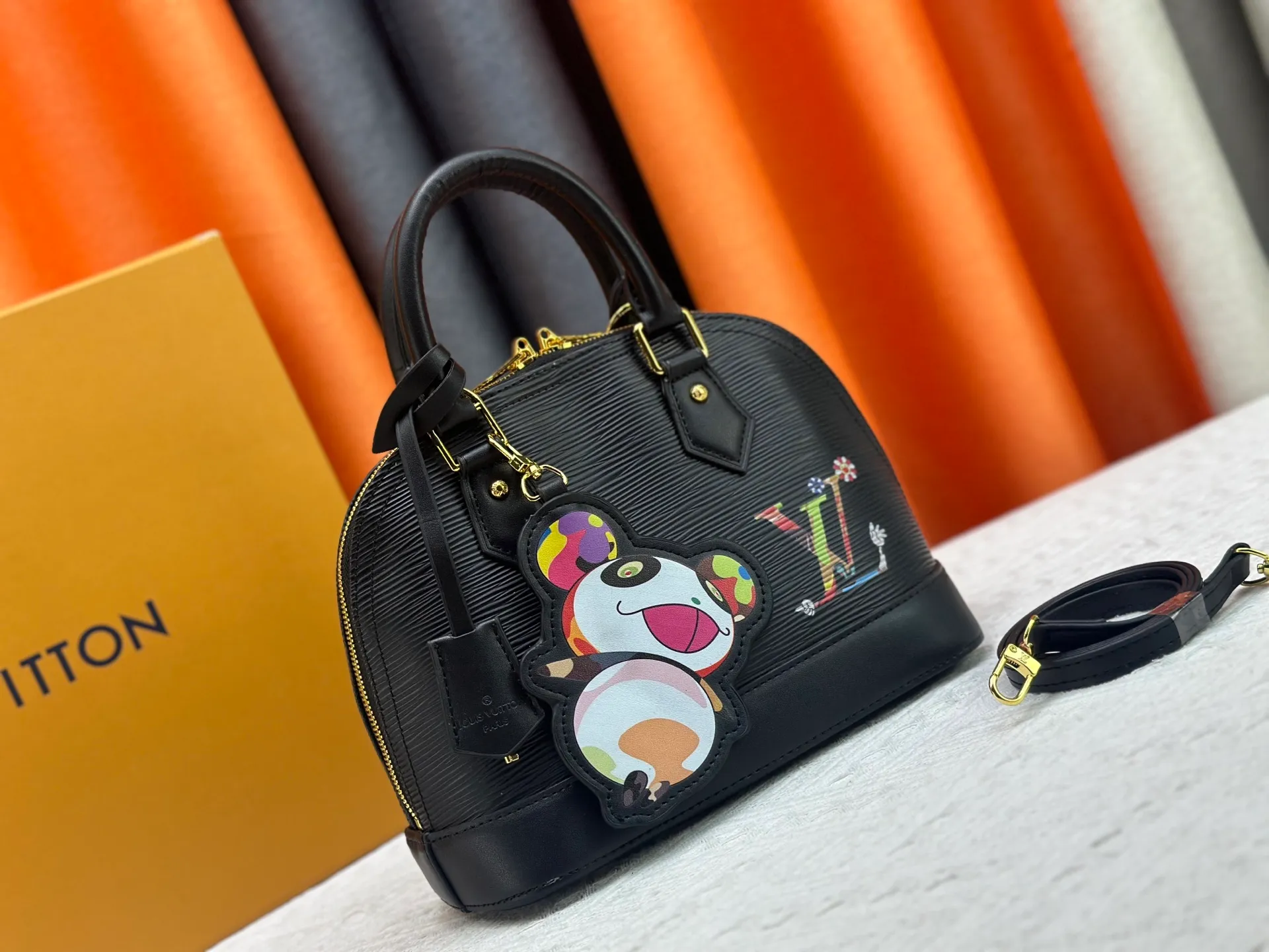 p300 Upgraded original M13670 M14197 M53152 This Alma BB handbag is made of Epi leather and appears in the Louis Vuitton x Murakami reissue series. The smart LV letters on the front reflect the Japanese artist's "ultra-flat" aesthetic, which contrasts with the removable distinctive panda decoration. Top handles, a removable shoulder strap and a dazzling padlock complete the Art Deco design. Dimensions: 23.5 x 17.5 x 11.5 cm (length x height x width)