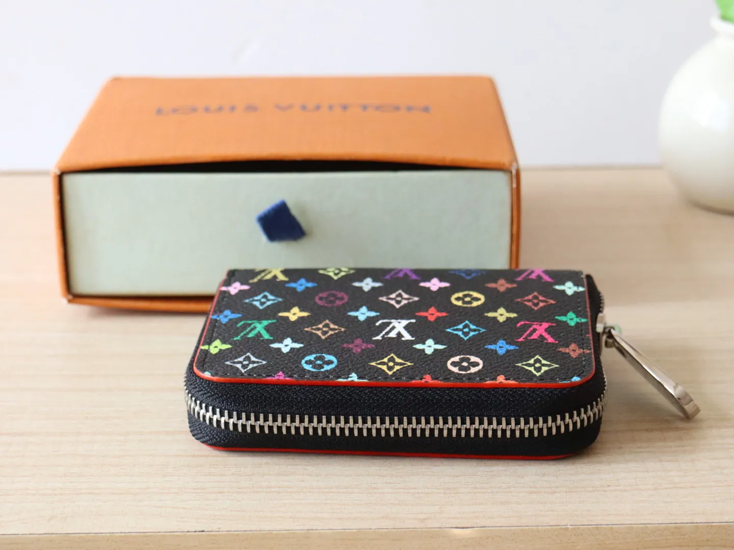13409 Tricolor Short Zipper Style 🌟P88 LV x TM Zippy Coin Purse M13409 White Color (Tricolor - Murakami) As part of the Louis Vuitton x Murakami series reissue, the timeless Zippy coin purse is practical and playful, upgraded for this season. It's made from Monogram coated canvas in a cheerful rainbow of hues, in keeping with the Japanese artist's signature pop palette. The interior is secured with a silver zipper and is divided into multiple compartments for coins, banknotes and cards. Dimensions: 11 x 8.5 x 2 cm.
