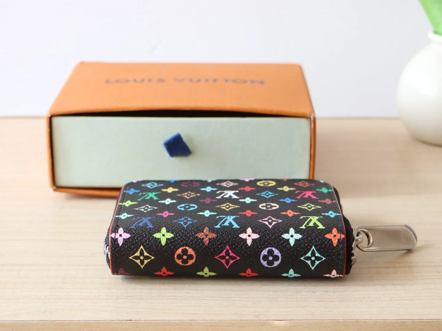 13409 Tricolor Short Zipper Style 🌟P88 LV x TM Zippy Coin Purse M13409 White Color (Tricolor - Murakami) As part of the Louis Vuitton x Murakami series reissue, the timeless Zippy coin purse is practical and playful, upgraded for this season. It's made from Monogram coated canvas in a cheerful rainbow of hues, in keeping with the Japanese artist's signature pop palette. The interior is secured with a silver zipper and is divided into multiple compartments for coins, banknotes and cards. Dimensions: 11 x 8.5 x 2 cm.