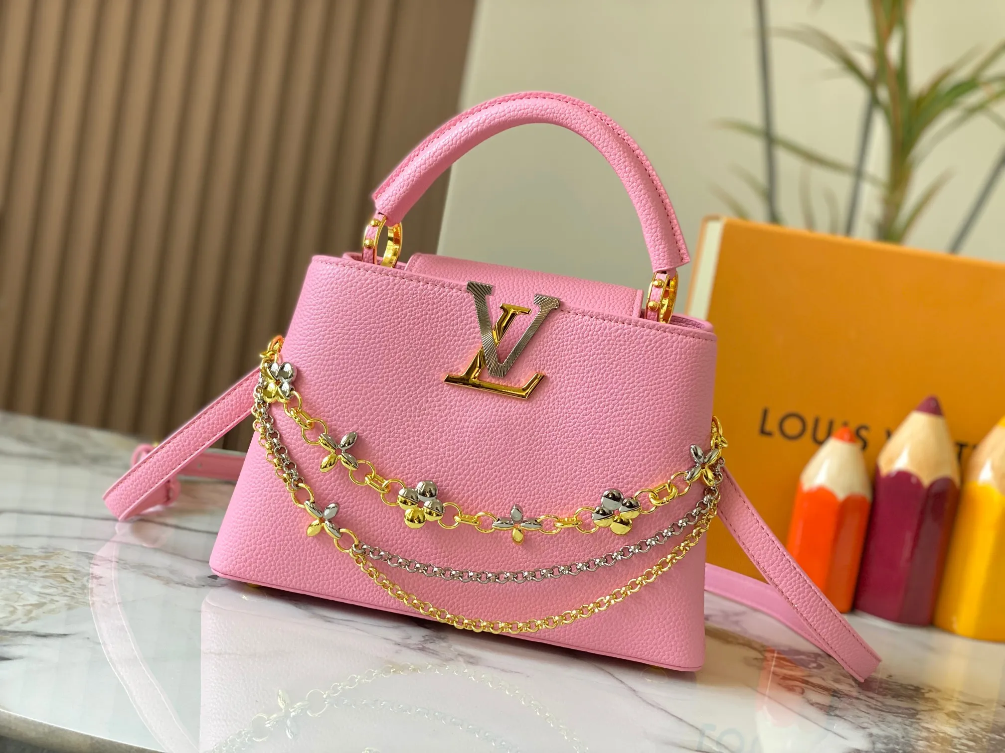 P500 [Guangzhou top quality original version] M26532 Pink This modern version of Capucines BB is made of timeless Taurillon leather and equipped with a jewelry-inspired Infinity chain. The bag is decorated with double galvanized metal parts, including the iconic Monogram floral pattern, and the LV Initials logo created with sunburst technology, creating a sundial-like light and shadow effect. The bag has multiple pockets and a detachable shoulder strap, allowing it to be carried on one shoulder or across the body. 27 x 17.3 x 9 (cm) (length x height x width)