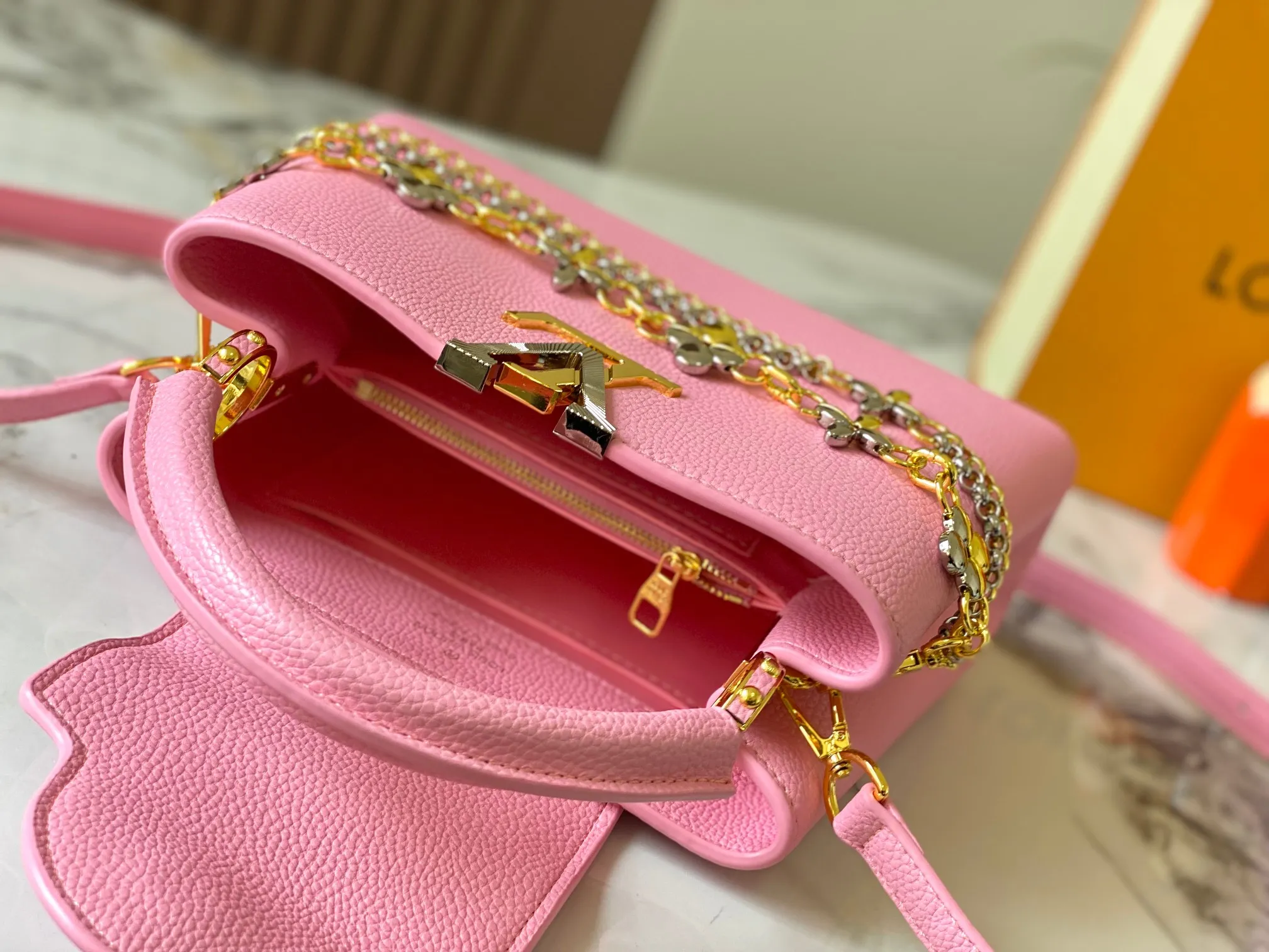 P500 [Guangzhou top quality original version] M26532 Pink This modern version of Capucines BB is made of timeless Taurillon leather and equipped with a jewelry-inspired Infinity chain. The bag is decorated with double galvanized metal parts, including the iconic Monogram floral pattern, and the LV Initials logo created with sunburst technology, creating a sundial-like light and shadow effect. The bag has multiple pockets and a detachable shoulder strap, allowing it to be carried on one shoulder or across the body. 27 x 17.3 x 9 (cm) (length x height x width)