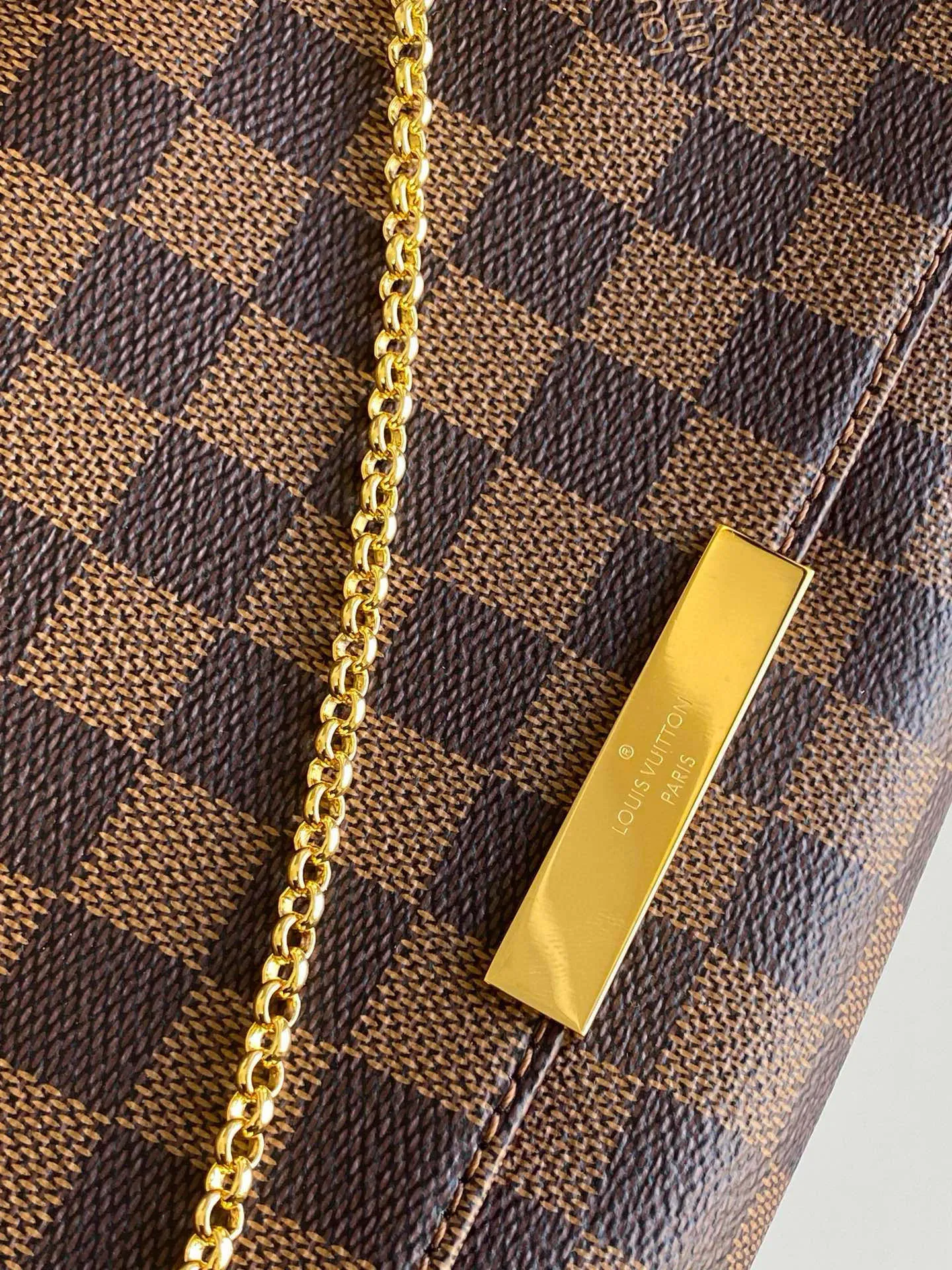 💰640 Top original item N41129 FAVORITE MM This Favorite MM handbag is the darling of fashionable women. It is sewn with geometric-style Damier Ebene canvas and is suitable for morning and evening occasions. The bag can be used as a clutch, or can be carried as a short shoulder bag using the gold chain strap, while the leather shoulder strap can be easily carried cross-body. An engraved metal plaque on the front conceals a clever magnetic closure for safe access. Details 26 x 15 x 4 cm (Length x Height x Width) Damier Ebene coated canvas Natural cowhide leather trim Textile lining Gold-tone hardware Magnetic flap closure Internal patch pocket Shoulder strap: Non-detachable, not adjustable Strap vertical height: 52.0 cm Chain strap: Detachable Chain strap vertical height: 17.0 cm