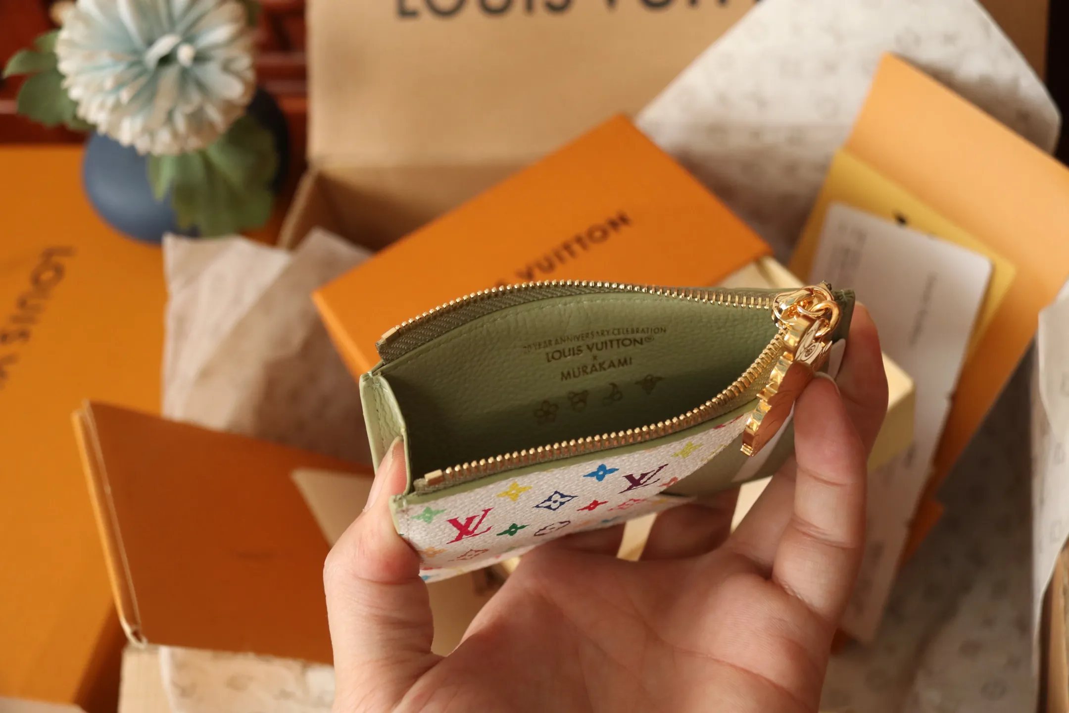 【LV x TM Romy Card Holder】 💎p400 m14155 rose m14171 blue m13800 green "LV × TM Porto Kurt Romy" appears in the "Louis Vuitton × Takashi Murakami" series that unfolds in a variety of categories. It features functional and playful expressions with fresh tones inspired by the rainbow colors unique to Japanese artists. The whole piece is finished with Monogram Amplant leather that adds a casual personality, and the bright Monogram multi-color canvas in the flat pocket stands out. The coin pocket opens and closes with a gold zipper and features a panda pull to symbolize the season.  Dimensions: 12 x 8 x 0.8 cm