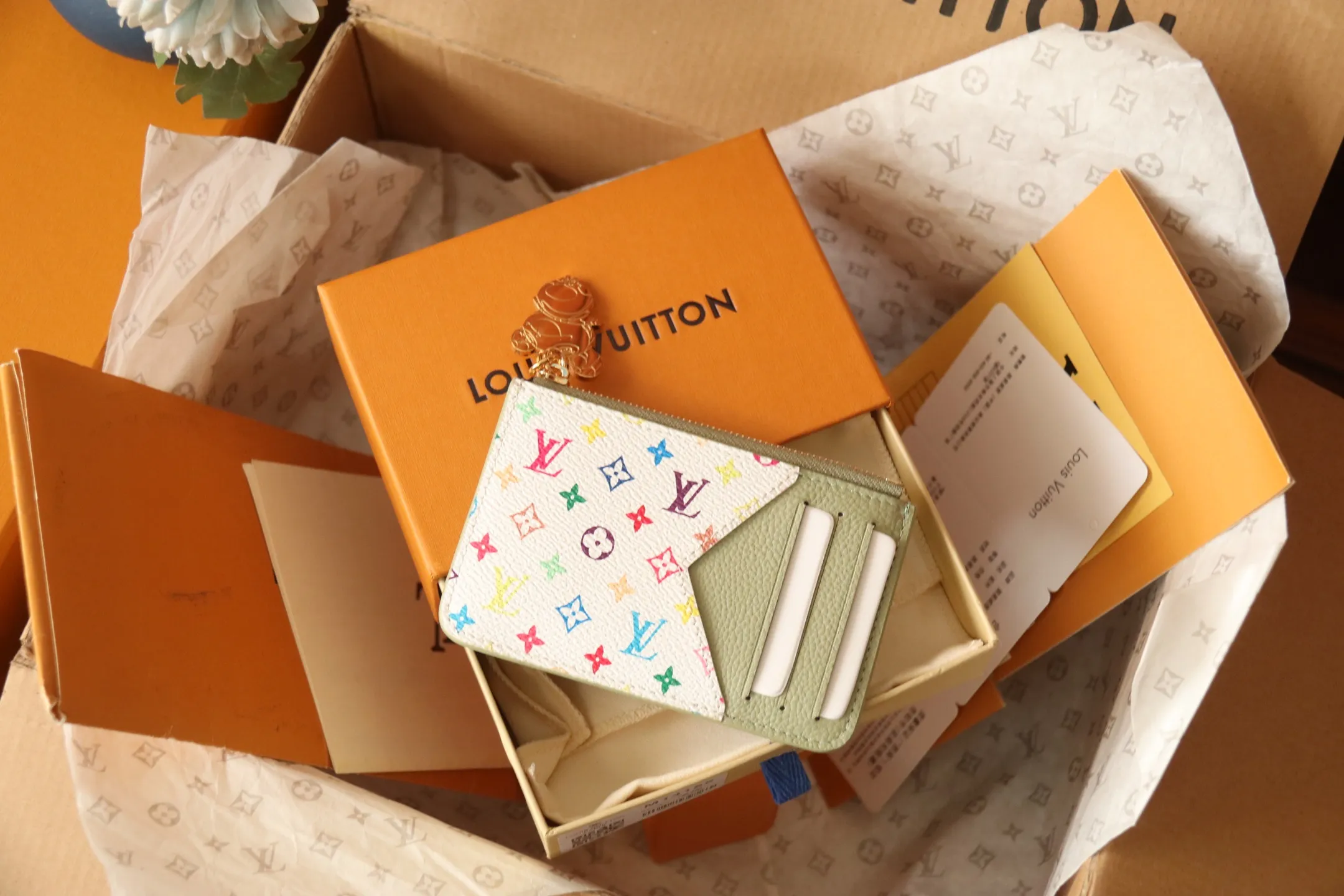 【LV x TM Romy Card Holder】 💎p400 m14155 rose m14171 blue m13800 green "LV × TM Porto Kurt Romy" appears in the "Louis Vuitton × Takashi Murakami" series that unfolds in a variety of categories. It features functional and playful expressions with fresh tones inspired by the rainbow colors unique to Japanese artists. The whole piece is finished with Monogram Amplant leather that adds a casual personality, and the bright Monogram multi-color canvas in the flat pocket stands out. The coin pocket opens and closes with a gold zipper and features a panda pull to symbolize the season.  Dimensions: 12 x 8 x 0.8 cm