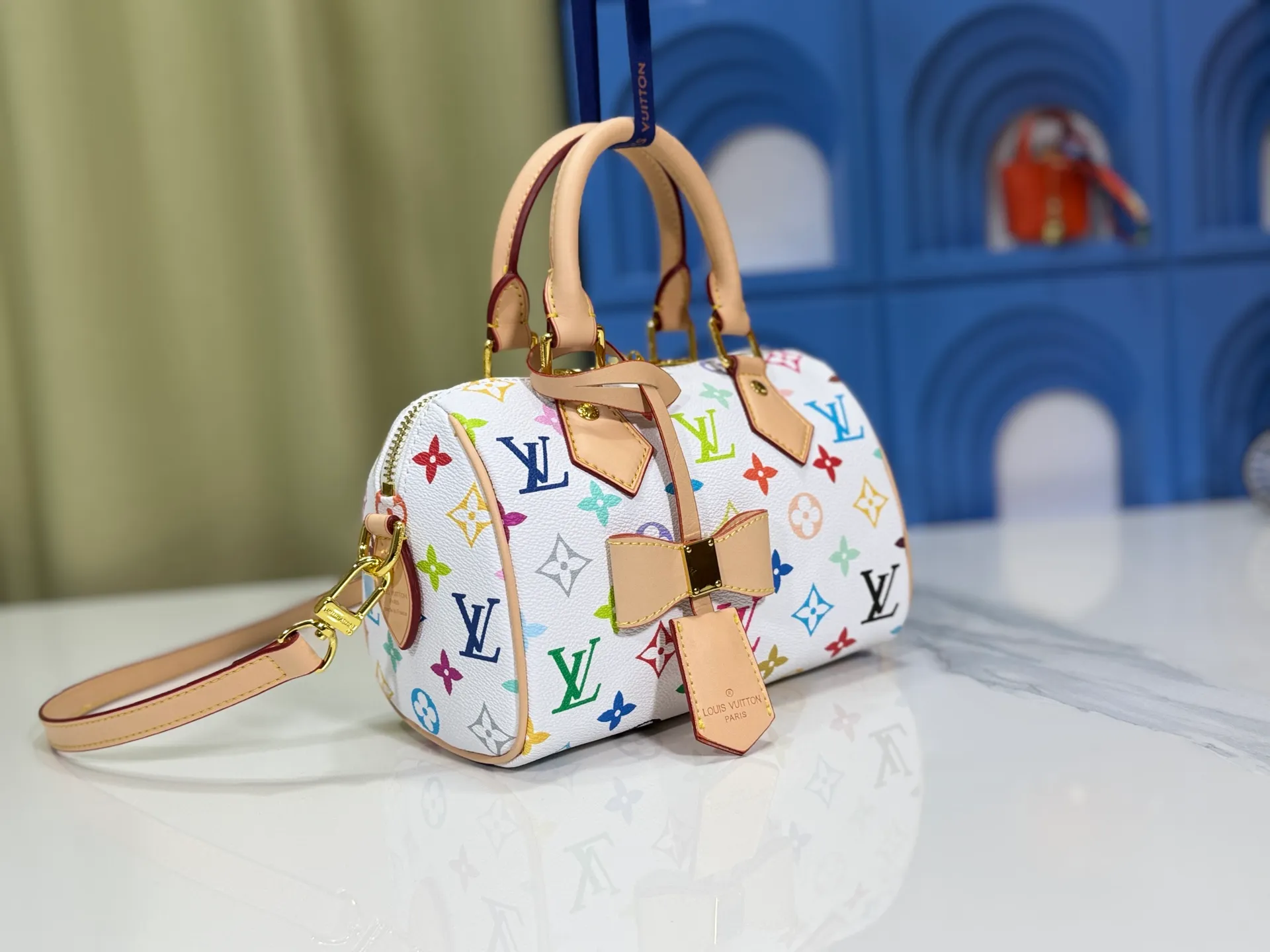P260 Upgraded from the original version, this M46234 M46222 Speedy Bandoulière 20 handbag is made of soft coated canvas, with the full-length Monogram pattern traced in colorful rainbow tones, highlighting the smart style of the Louis Vuitton x Murakami reissue series. The Toron handle and detachable shoulder strap are constructed of cow leather, the metal corners recall classic luggage elements, and the bow-shaped key bag and padlock add brand touches. Dimensions: 20.5 x 13.5 x 12.0 cm (length x height x width)