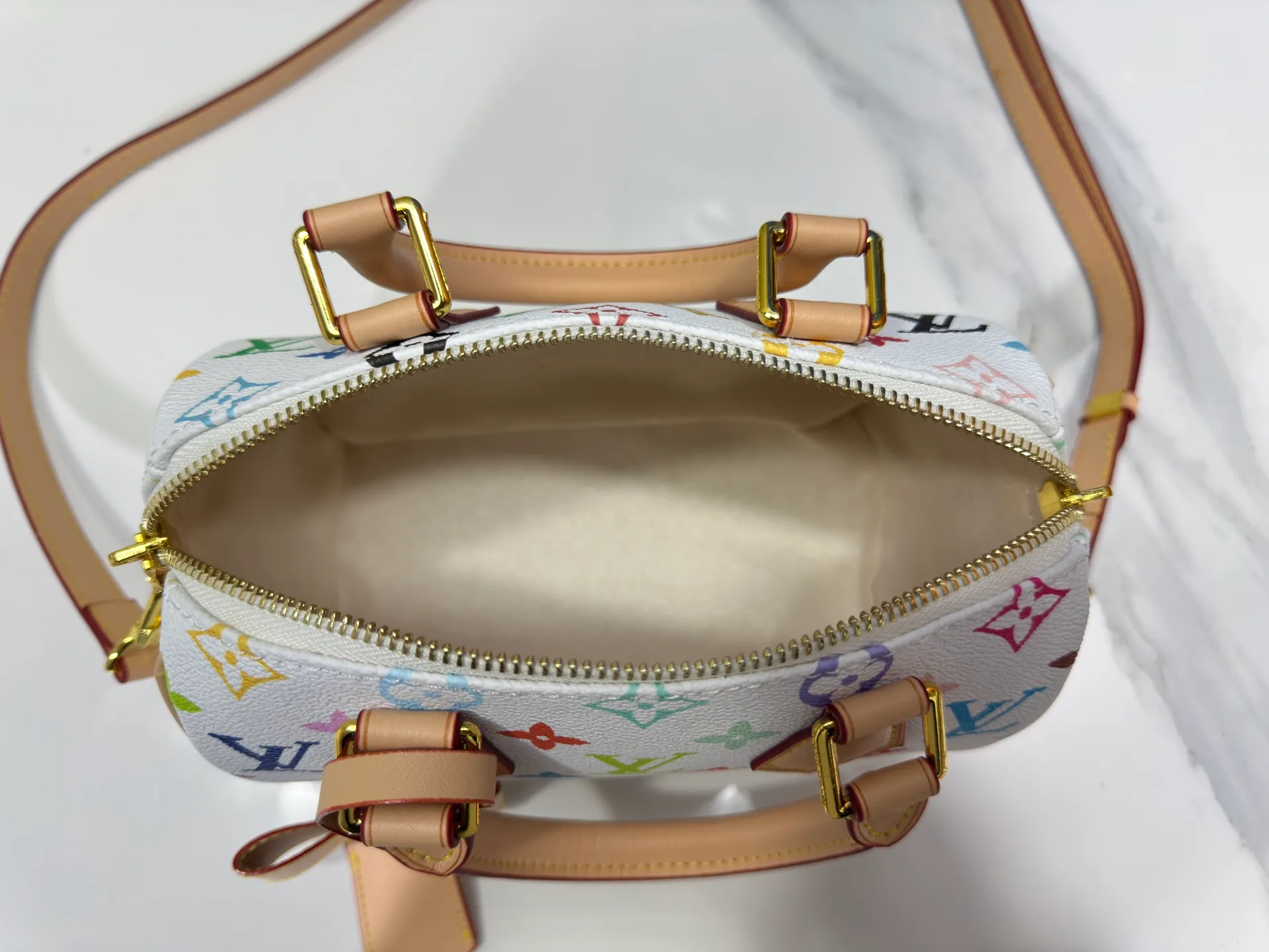 P260 Upgraded from the original version, this M46234 M46222 Speedy Bandoulière 20 handbag is made of soft coated canvas, with the full-length Monogram pattern traced in colorful rainbow tones, highlighting the smart style of the Louis Vuitton x Murakami reissue series. The Toron handle and detachable shoulder strap are constructed of cow leather, the metal corners recall classic luggage elements, and the bow-shaped key bag and padlock add brand touches. Dimensions: 20.5 x 13.5 x 12.0 cm (length x height x width)