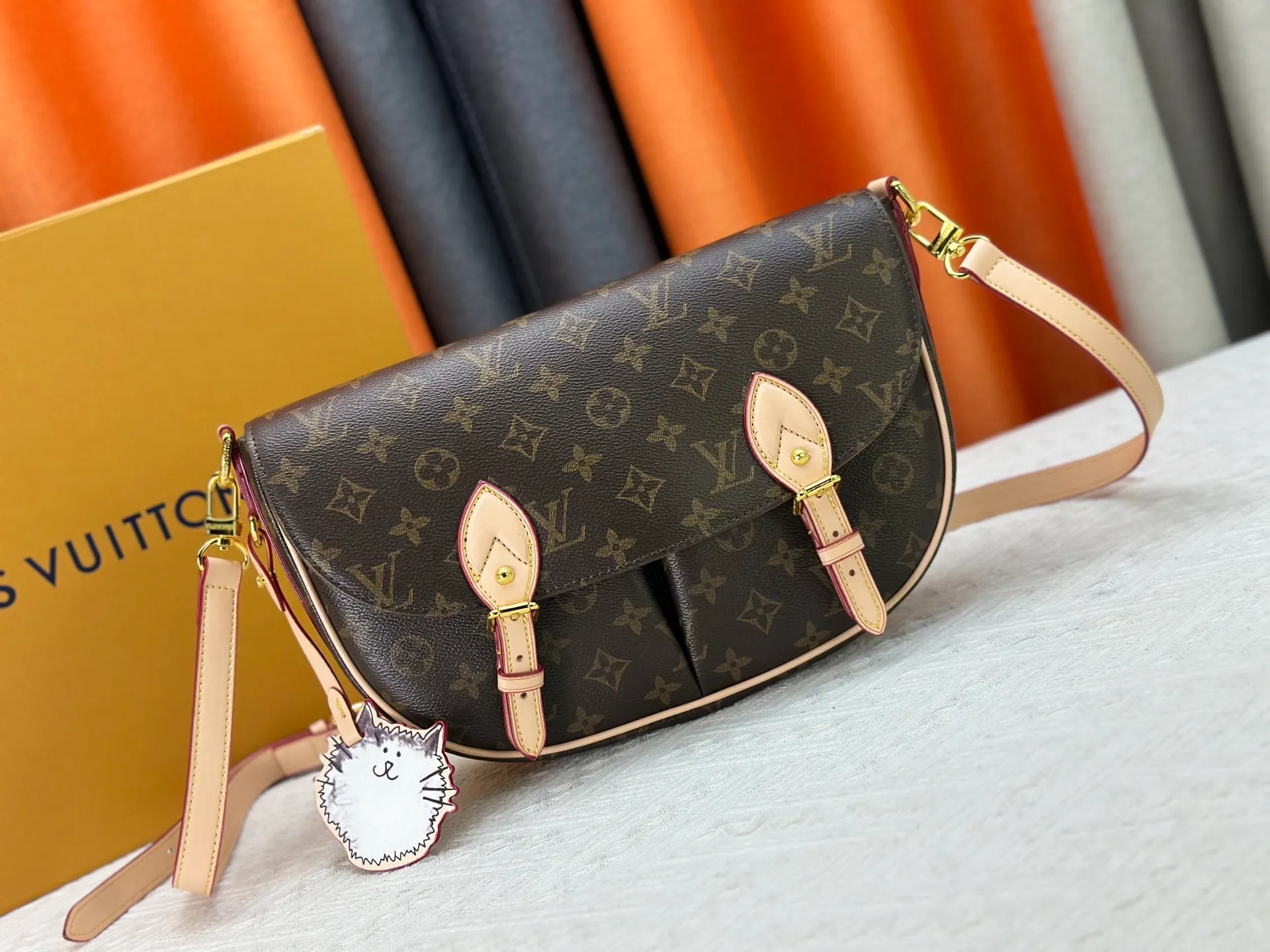 The P300 M15134 Escape handbag makes an eye-catching appearance in the LV Travels With Grace Coddington series. It is a canvas bag with a fun Meowgram pattern and a cat-shaped leather decoration hand-painted by Coddington himself. The flexible design provides a variety of carrying methods and can easily accommodate various daily needs. Dimensions: 21 x 7 x 30 cm