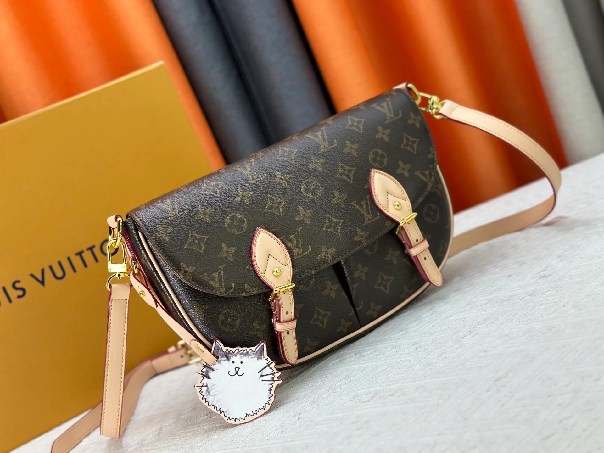 The P300 M15134 Escape handbag makes an eye-catching appearance in the LV Travels With Grace Coddington series. It is a canvas bag with a fun Meowgram pattern and a cat-shaped leather decoration hand-painted by Coddington himself. The flexible design provides a variety of carrying methods and can easily accommodate various daily needs. Dimensions: 21 x 7 x 30 cm