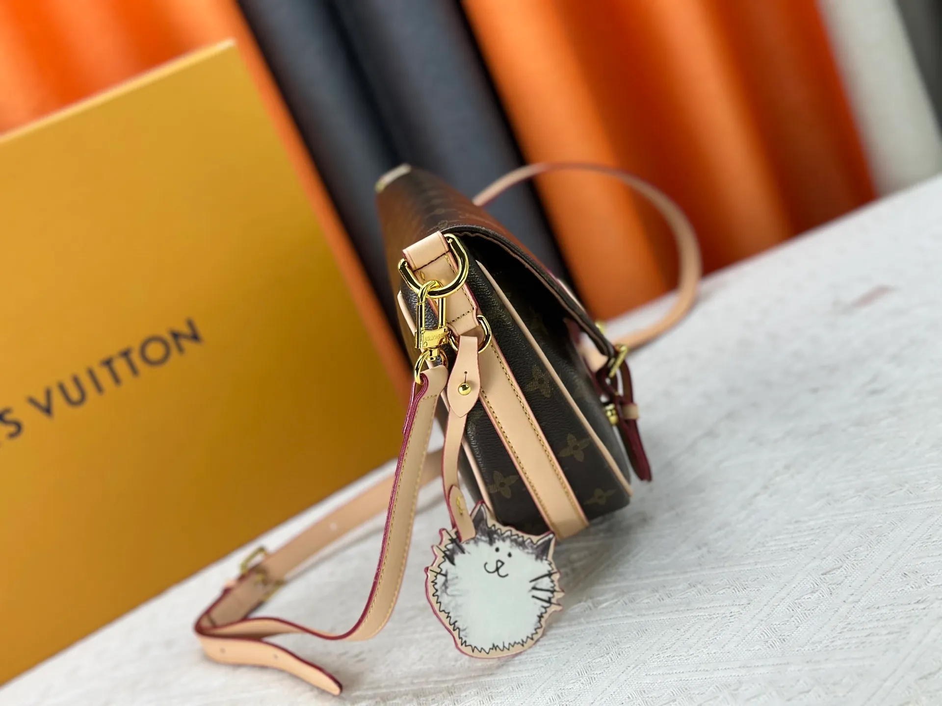 The P300 M15134 Escape handbag makes an eye-catching appearance in the LV Travels With Grace Coddington series. It is a canvas bag with a fun Meowgram pattern and a cat-shaped leather decoration hand-painted by Coddington himself. The flexible design provides a variety of carrying methods and can easily accommodate various daily needs. Dimensions: 21 x 7 x 30 cm