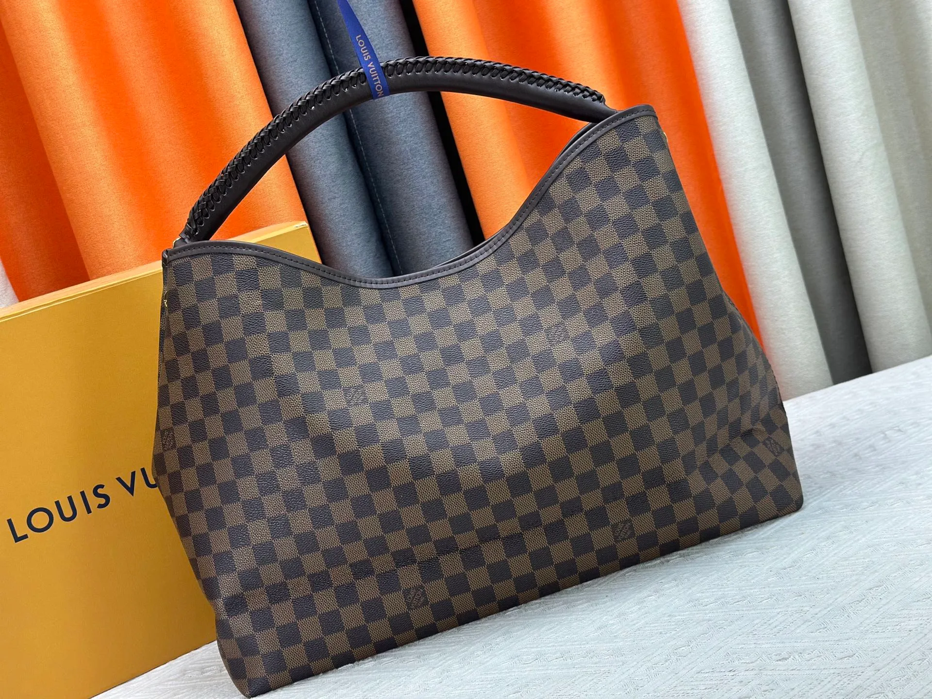 P300 upgrades the original M25877 Again bag, a new interpretation of the iconic Artsy design first launched in 2010, now more flexible, more iconic and more refined. Rooted in LV’s DNA, this bag pays homage to Louis Vuitton’s craftsmanship with its classic Monogram canvas base, hand-woven handles and customizable name tag. It's spacious enough to hold a laptop and opens to reveal multiple pockets. Gold hooks can be used to hang playful accessories! ! Size:50x30x15.5CM