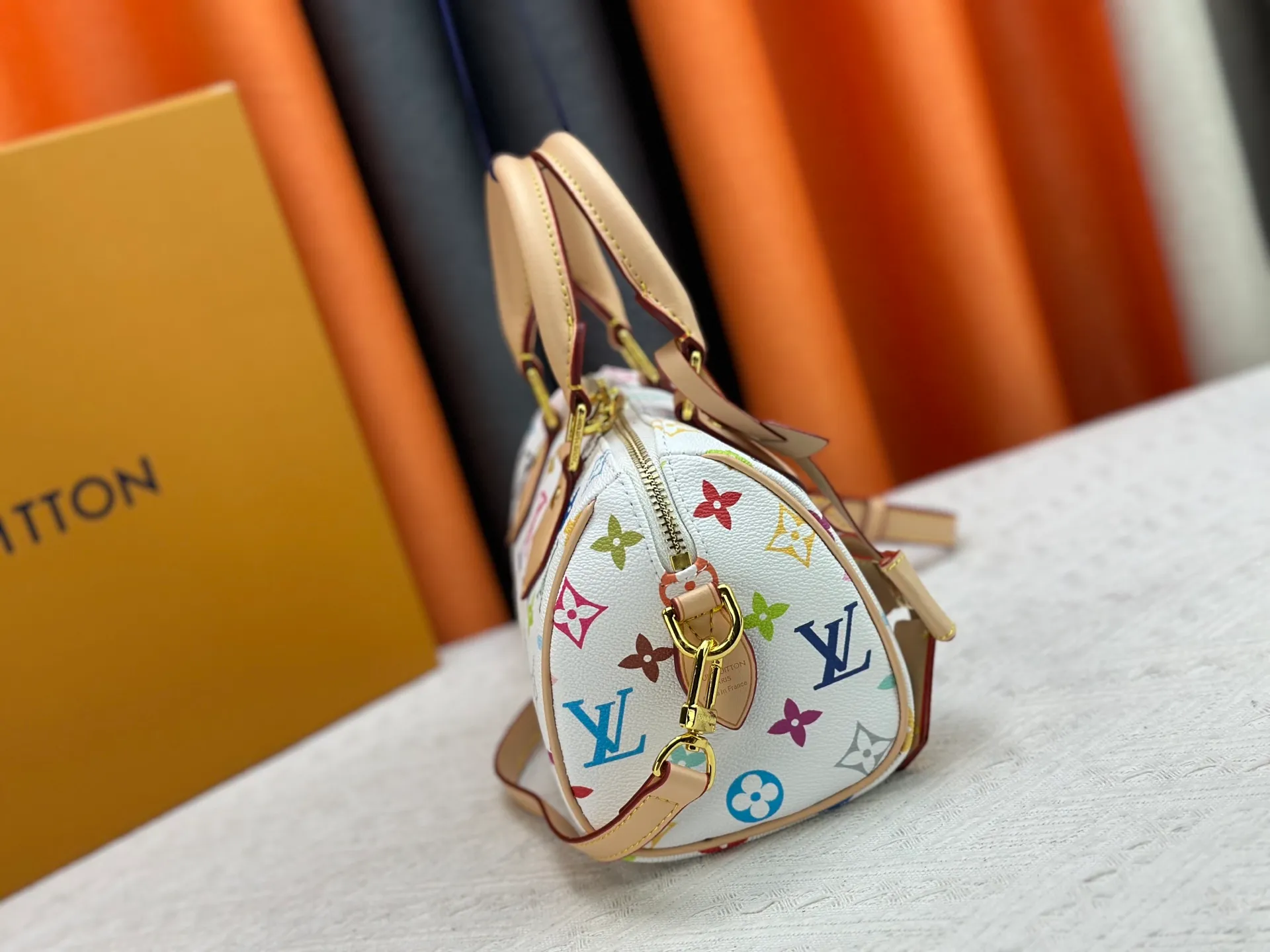 P260 Upgraded from the original version, this M46234 M46222 Speedy Bandoulière 20 handbag is made of soft coated canvas, with the full-length Monogram pattern traced in colorful rainbow tones, highlighting the smart style of the Louis Vuitton x Murakami reissue series. The Toron handle and detachable shoulder strap are constructed of cow leather, the metal corners recall classic luggage elements, and the bow-shaped key bag and padlock add brand touches. Dimensions: 20.5 x 13.5 x 12.0 cm (length x height x width)