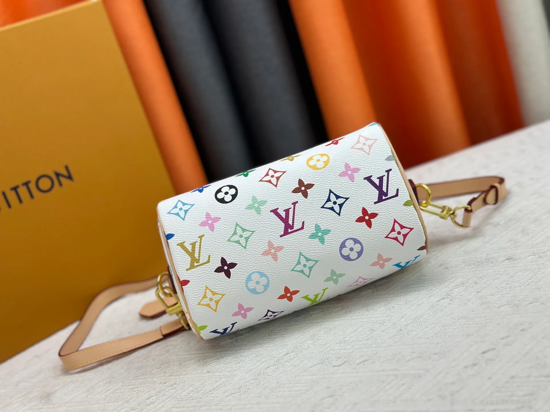 P260 Upgraded from the original version, this M46234 M46222 Speedy Bandoulière 20 handbag is made of soft coated canvas, with the full-length Monogram pattern traced in colorful rainbow tones, highlighting the smart style of the Louis Vuitton x Murakami reissue series. The Toron handle and detachable shoulder strap are constructed of cow leather, the metal corners recall classic luggage elements, and the bow-shaped key bag and padlock add brand touches. Dimensions: 20.5 x 13.5 x 12.0 cm (length x height x width)