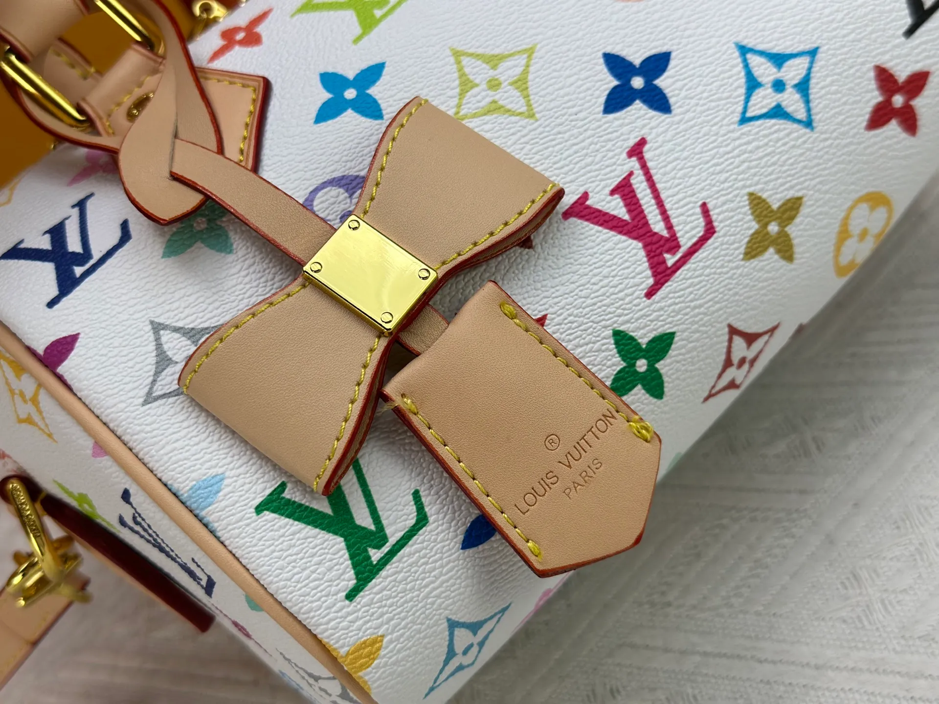 P260 Upgraded from the original version, this M46234 M46222 Speedy Bandoulière 20 handbag is made of soft coated canvas, with the full-length Monogram pattern traced in colorful rainbow tones, highlighting the smart style of the Louis Vuitton x Murakami reissue series. The Toron handle and detachable shoulder strap are constructed of cow leather, the metal corners recall classic luggage elements, and the bow-shaped key bag and padlock add brand touches. Dimensions: 20.5 x 13.5 x 12.0 cm (length x height x width)
