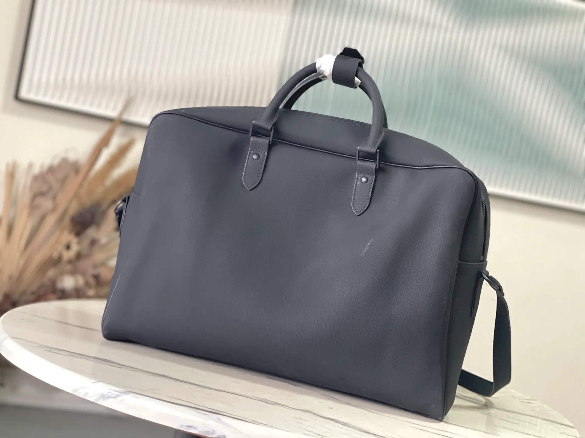 💰1680 (first-grain leather) Top-quality original order M26075 This Weekender Bag handbag is made of waxed cow leather, lining of the same color and bright metal parts. Its size is just right to be placed on the top of the Horizon trolley suitcase, making business travel easy and comfortable. A roomy zippered front pocket expands the main compartment, while a top handle and removable and adjustable shoulder strap provide multiple carrying options. Dimensions: 46 × 31 × 8 cm