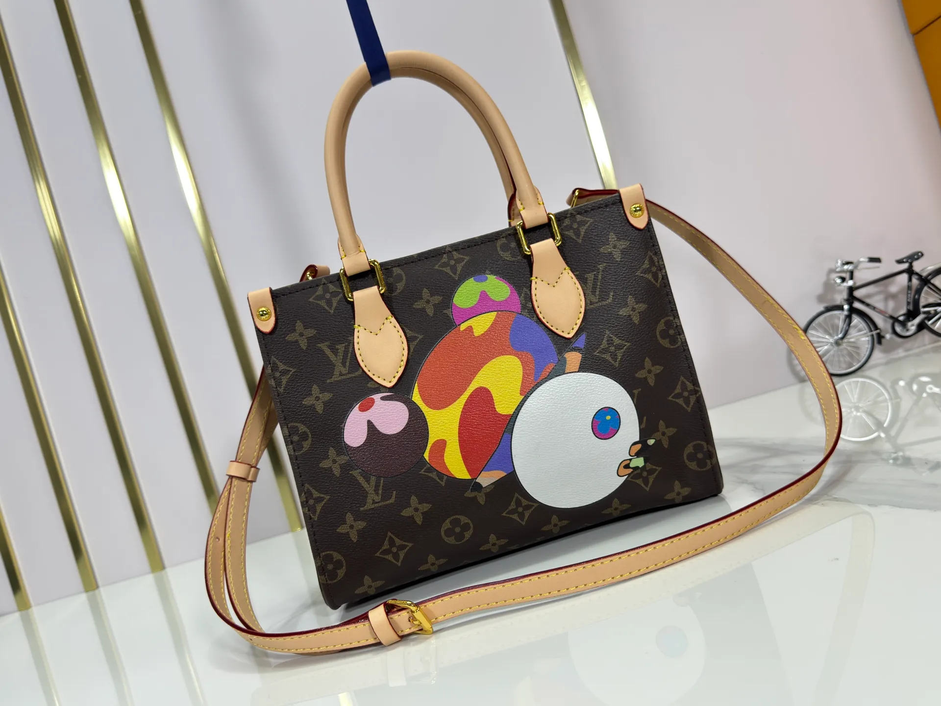 P240 upgraded original M45659 M46373 M13668 M44571 The Louis Vuitton x Murakami reissue series interprets the exquisite version of the OnTheGo handbag with playful touches. Monogram canvas and cow leather establish the brand's classic style, and Murakami's cute and cute panda image is transformed into front and back prints. The detachable and adjustable shoulder strap provides a variety of carrying options, and the zippered interior pocket keeps personal items safe and secure. Dimensions: 25.0 x 19.0 x 11.5 cm (length x height x width)