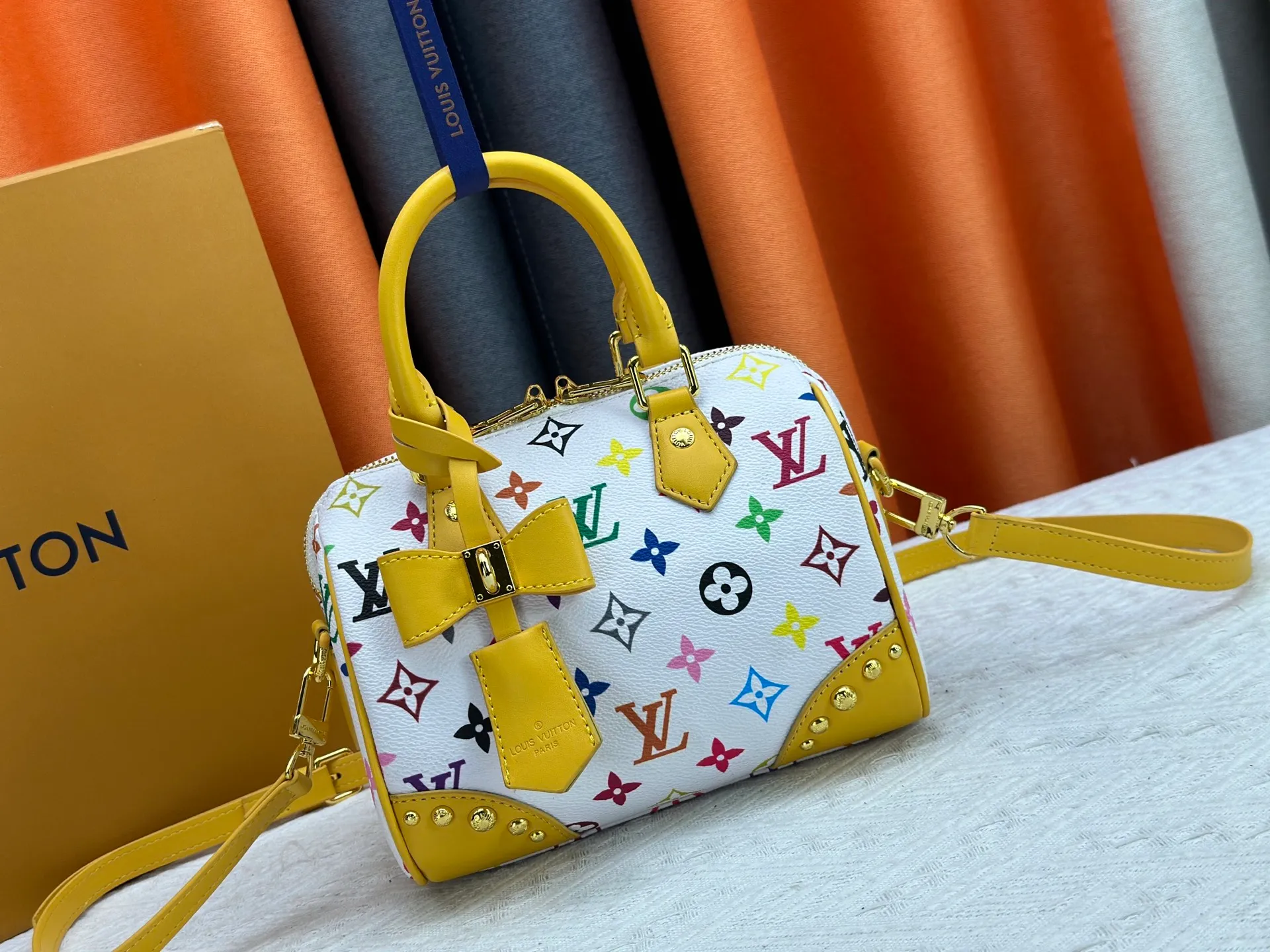 P260 upgraded original M58953 M46234 M46222 Speedy Bandoulière 20 handbag is made of soft coated canvas, and the full-length Monogram pattern is traced in colorful rainbow tones, highlighting the smart style of the Louis Vuitton x Murakami reissue series. The Toron handle and detachable shoulder strap are constructed of cow leather, the metal corners recall classic luggage elements, and the bow-shaped key bag and padlock add brand touches. Dimensions: 20.5 x 13.5 x 12.0 cm (length x height x width)