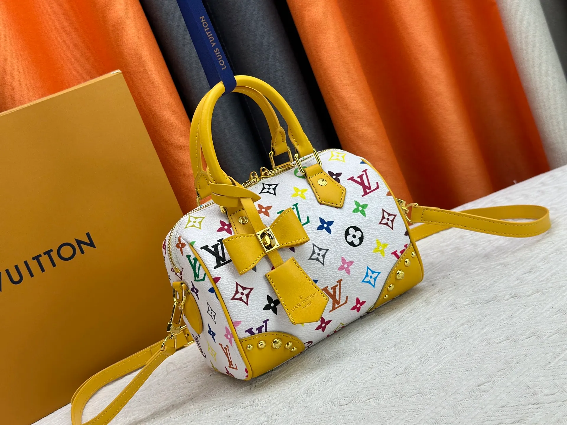P260 upgraded original M58953 M46234 M46222 Speedy Bandoulière 20 handbag is made of soft coated canvas, and the full-length Monogram pattern is traced in colorful rainbow tones, highlighting the smart style of the Louis Vuitton x Murakami reissue series. The Toron handle and detachable shoulder strap are constructed of cow leather, the metal corners recall classic luggage elements, and the bow-shaped key bag and padlock add brand touches. Dimensions: 20.5 x 13.5 x 12.0 cm (length x height x width)