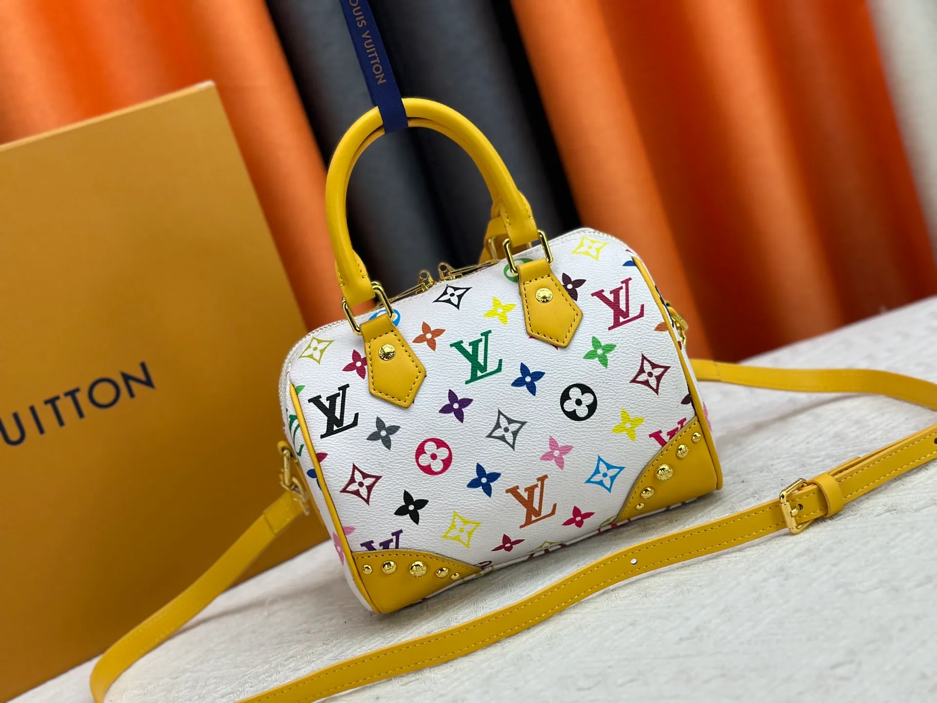 P260 upgraded original M58953 M46234 M46222 Speedy Bandoulière 20 handbag is made of soft coated canvas, and the full-length Monogram pattern is traced in colorful rainbow tones, highlighting the smart style of the Louis Vuitton x Murakami reissue series. The Toron handle and detachable shoulder strap are constructed of cow leather, the metal corners recall classic luggage elements, and the bow-shaped key bag and padlock add brand touches. Dimensions: 20.5 x 13.5 x 12.0 cm (length x height x width)